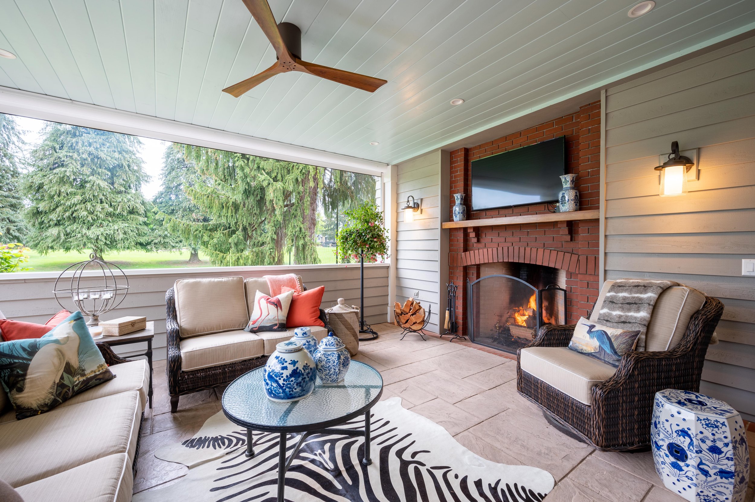 Covered patio with outdoor seating, fireplace, and ceiling fan