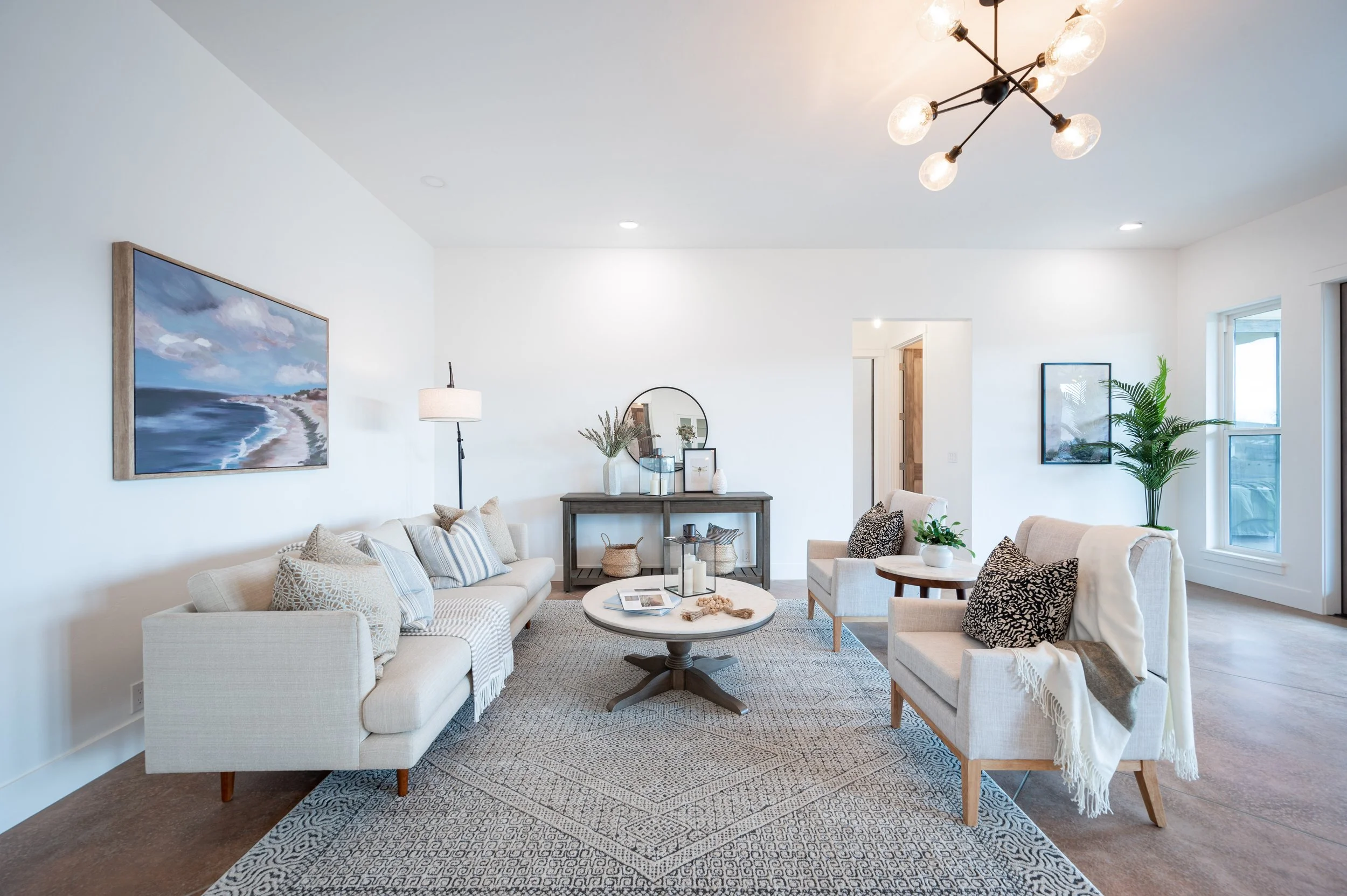 Living room with neutral seating, area rug, round coffee table, and modern ceiling light