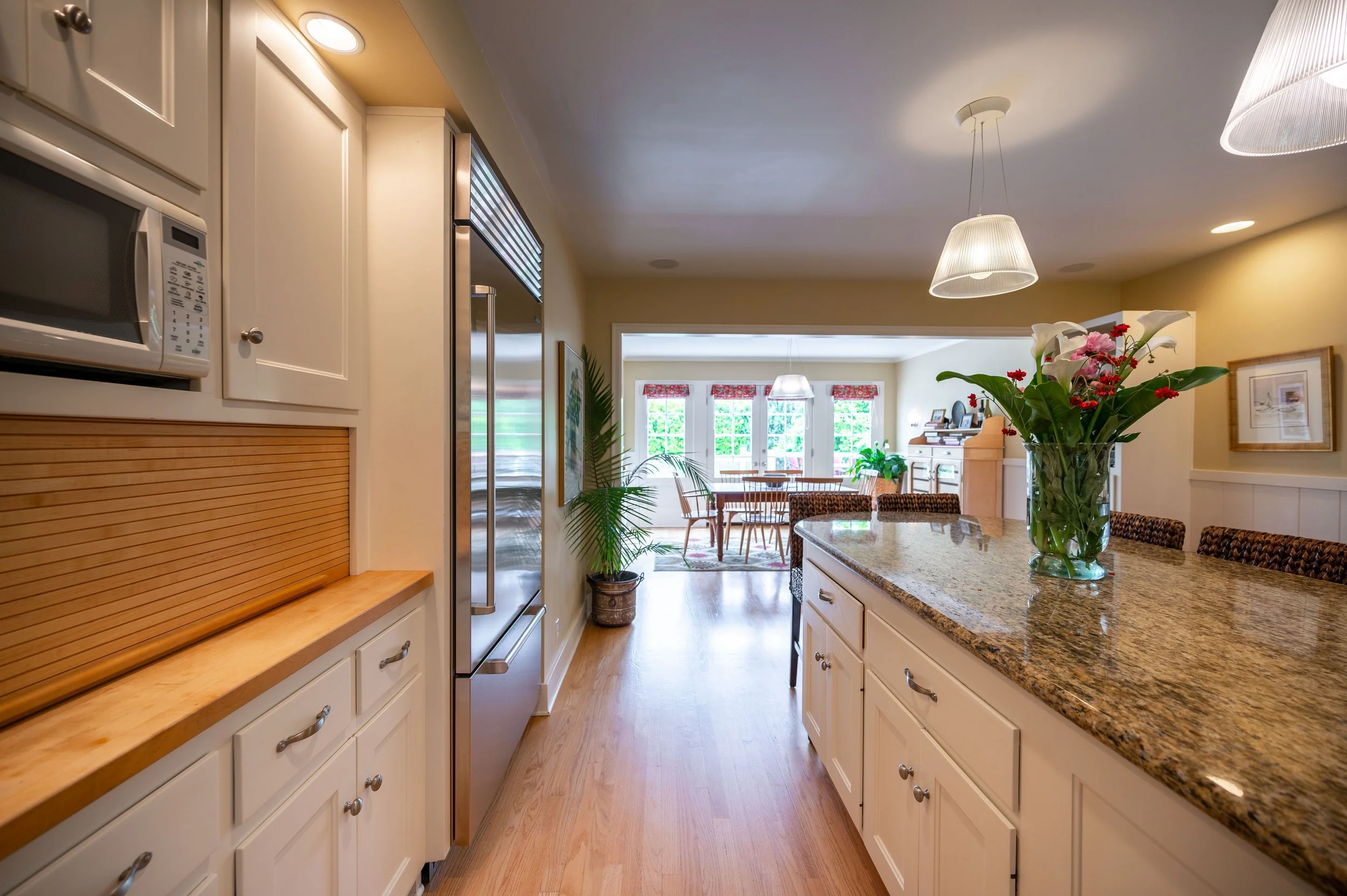 Kitchen view toward breakfast nook with large windows and wood floors