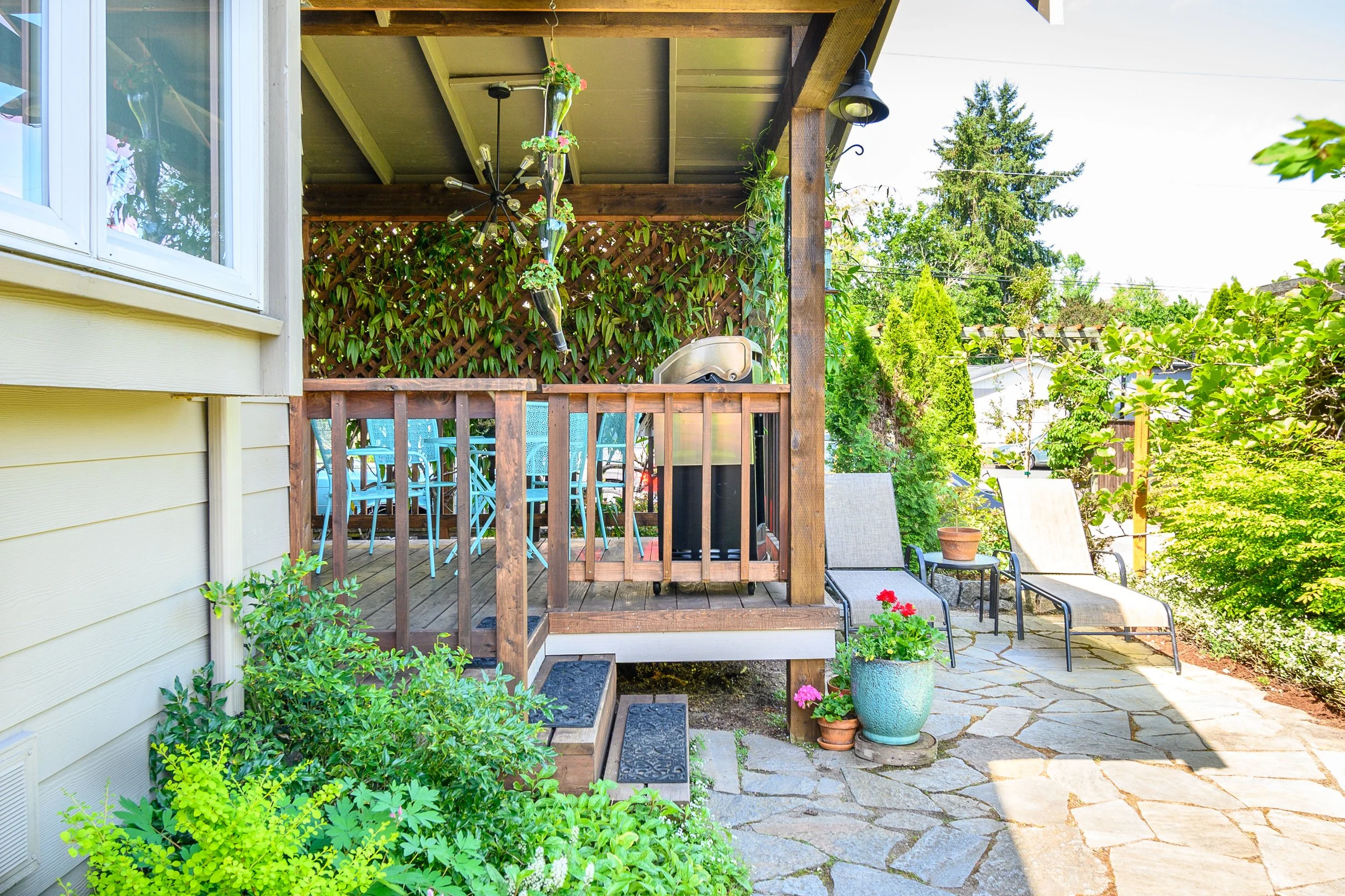 Covered porch with seating, potted plants, and stone walkway