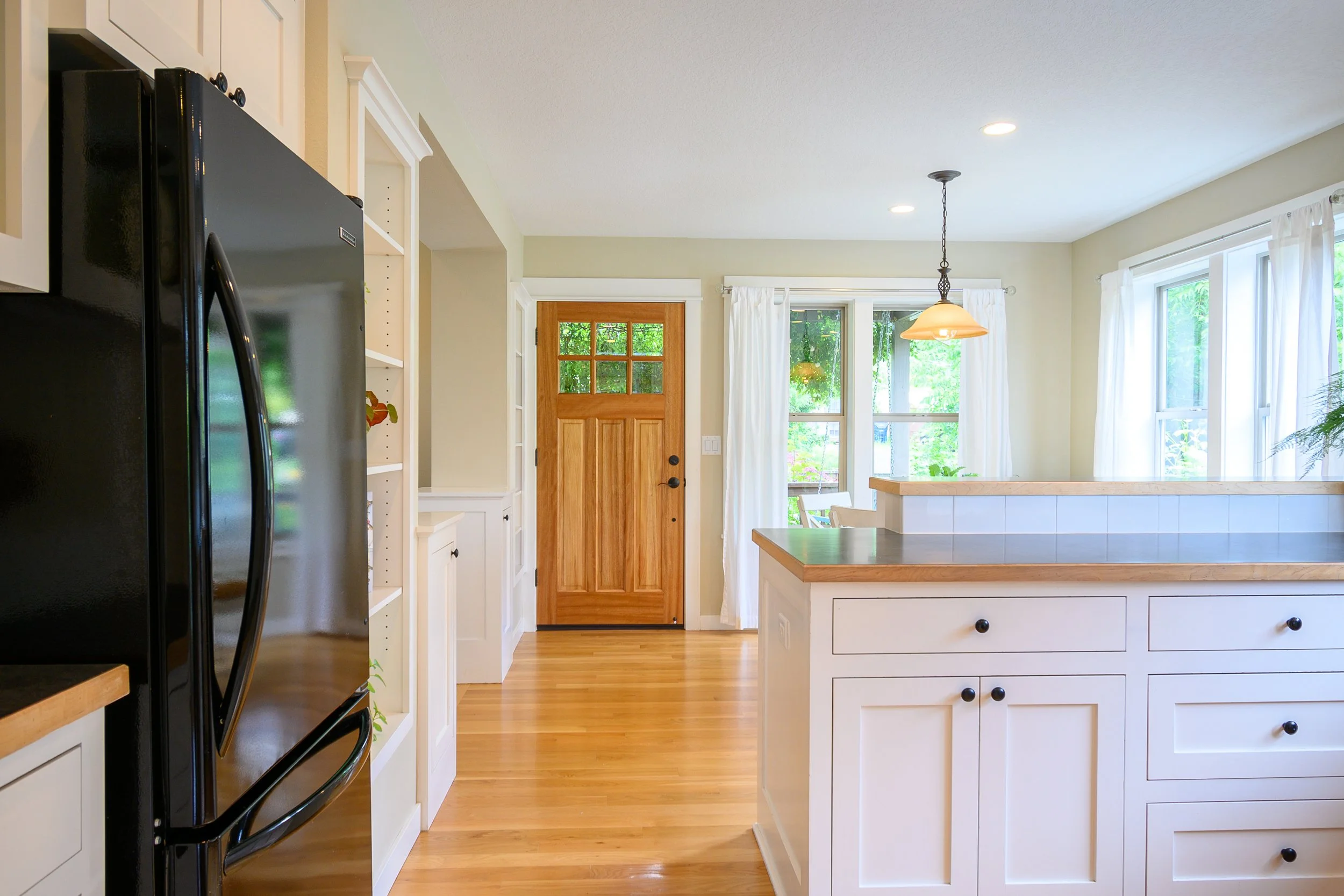 Kitchen entry with center island, wood floors, and natural light