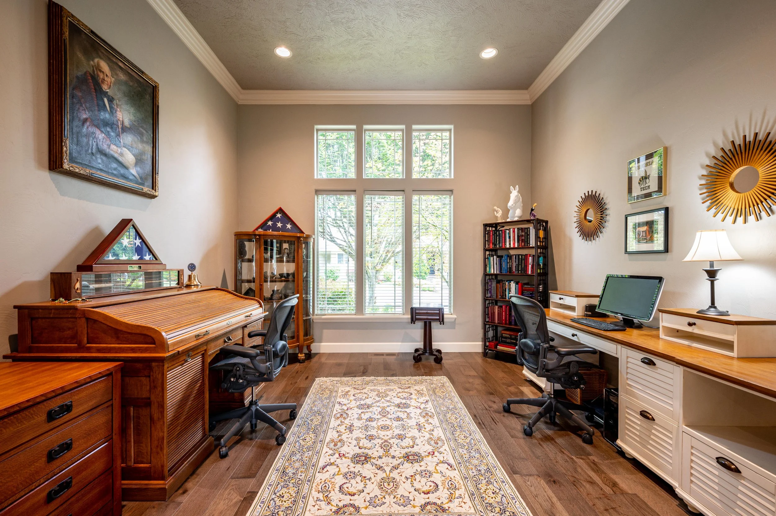 Home office with built-in desk, bookshelves, and large windows