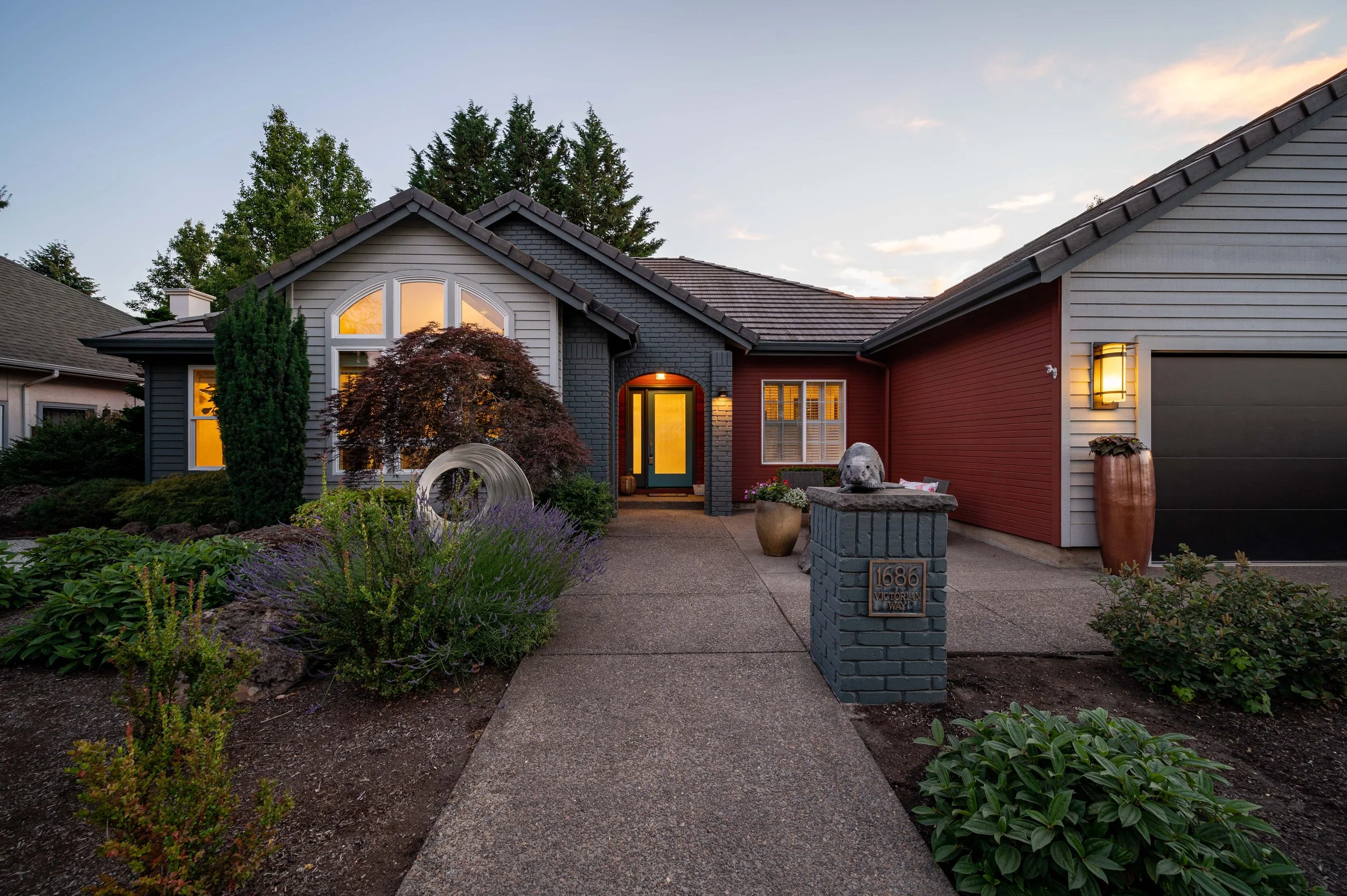 Front entry walkway at dusk with illuminated doorway and landscaped approach