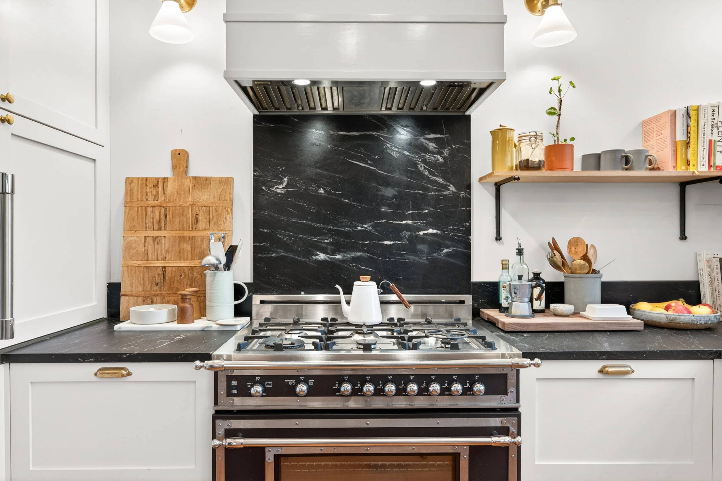Detail shot of a luxury white kitchen featuring a marble backsplash and gas range
