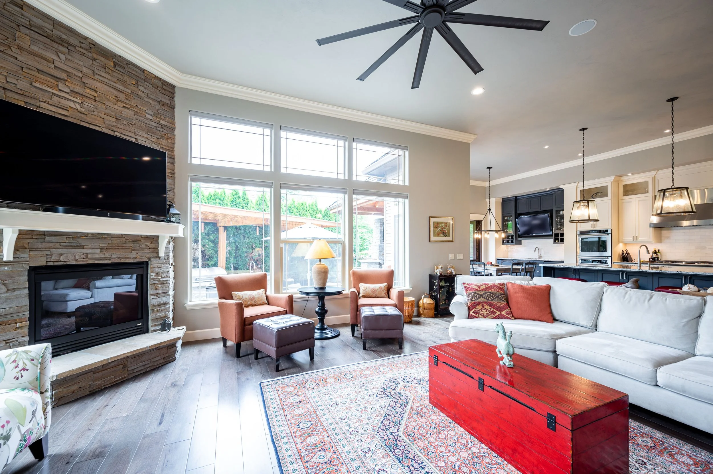 Living room with tall windows, ceiling fan, fireplace, and open layout