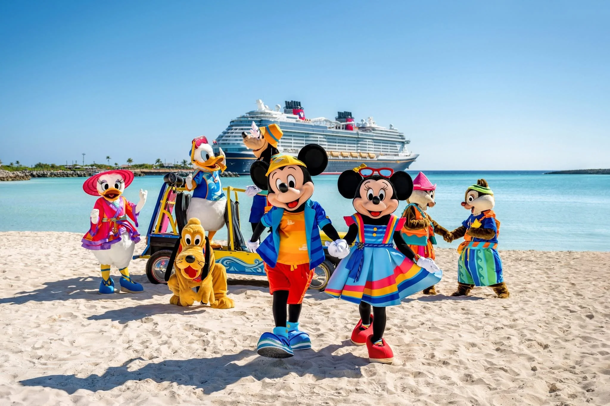 Disney characters Mickey Mouse, Minnie Mouse, Donald Duck, Daisy Duck, Goofy, Pluto, and Chip and Dale in colorful beach clothes on a sandy beach with a cruise ship in the background.