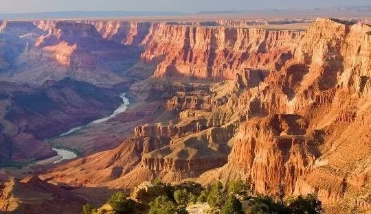 The Grand Canyon with layered red and orange cliffs and a winding river at the bottom.