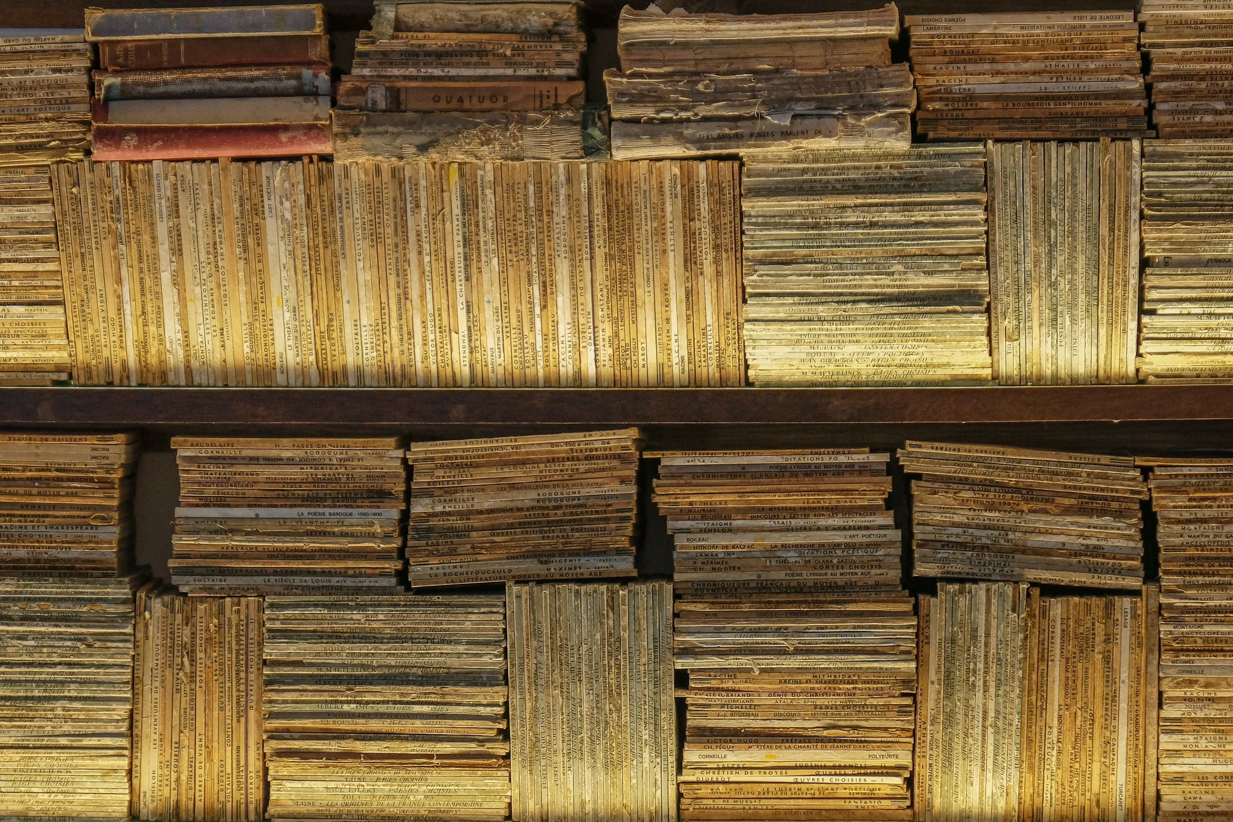 A large collection of aged, worn books and magazines stacked on shelves.