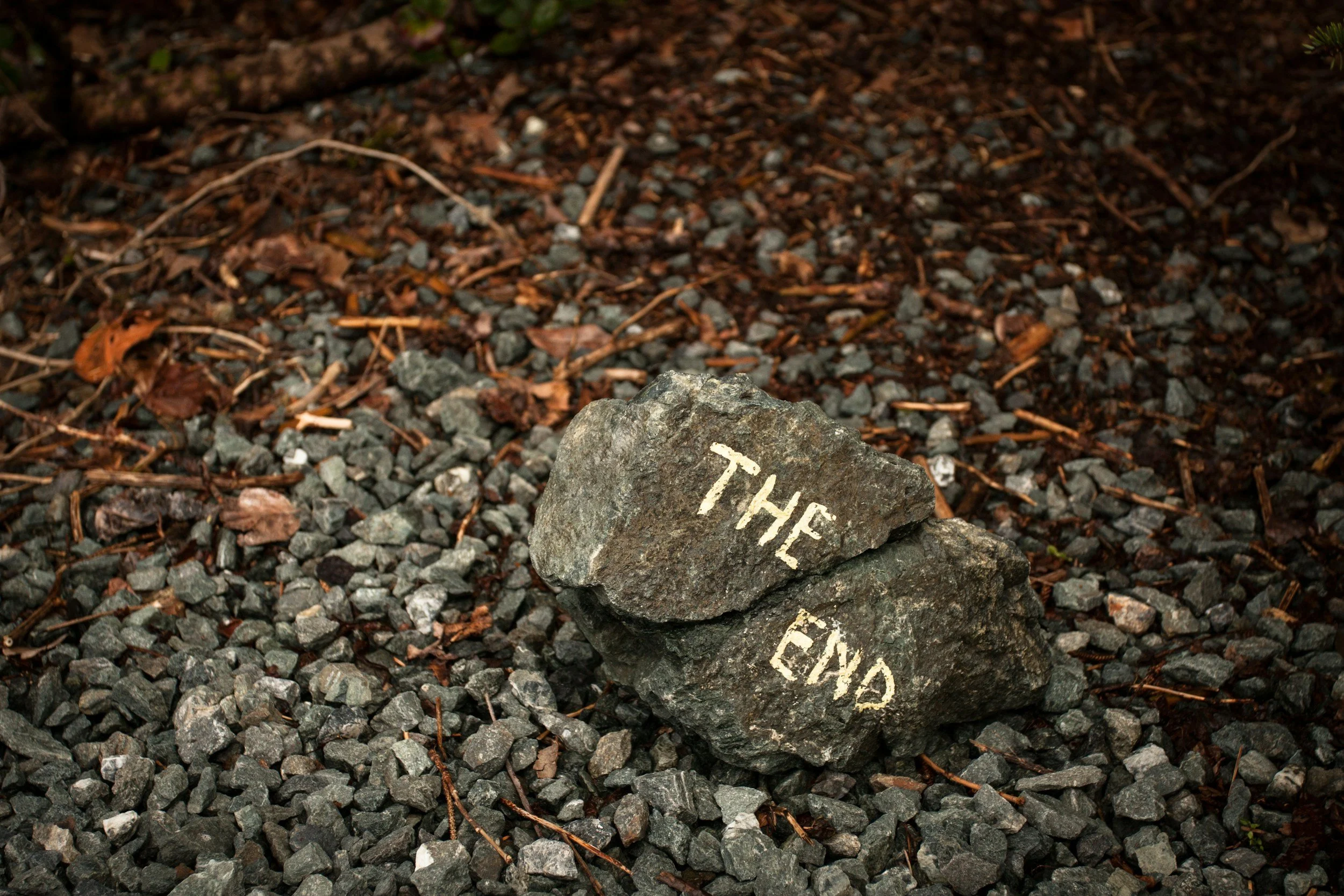 Two rocks on gravel ground with the words 'THE END' painted in white on them.