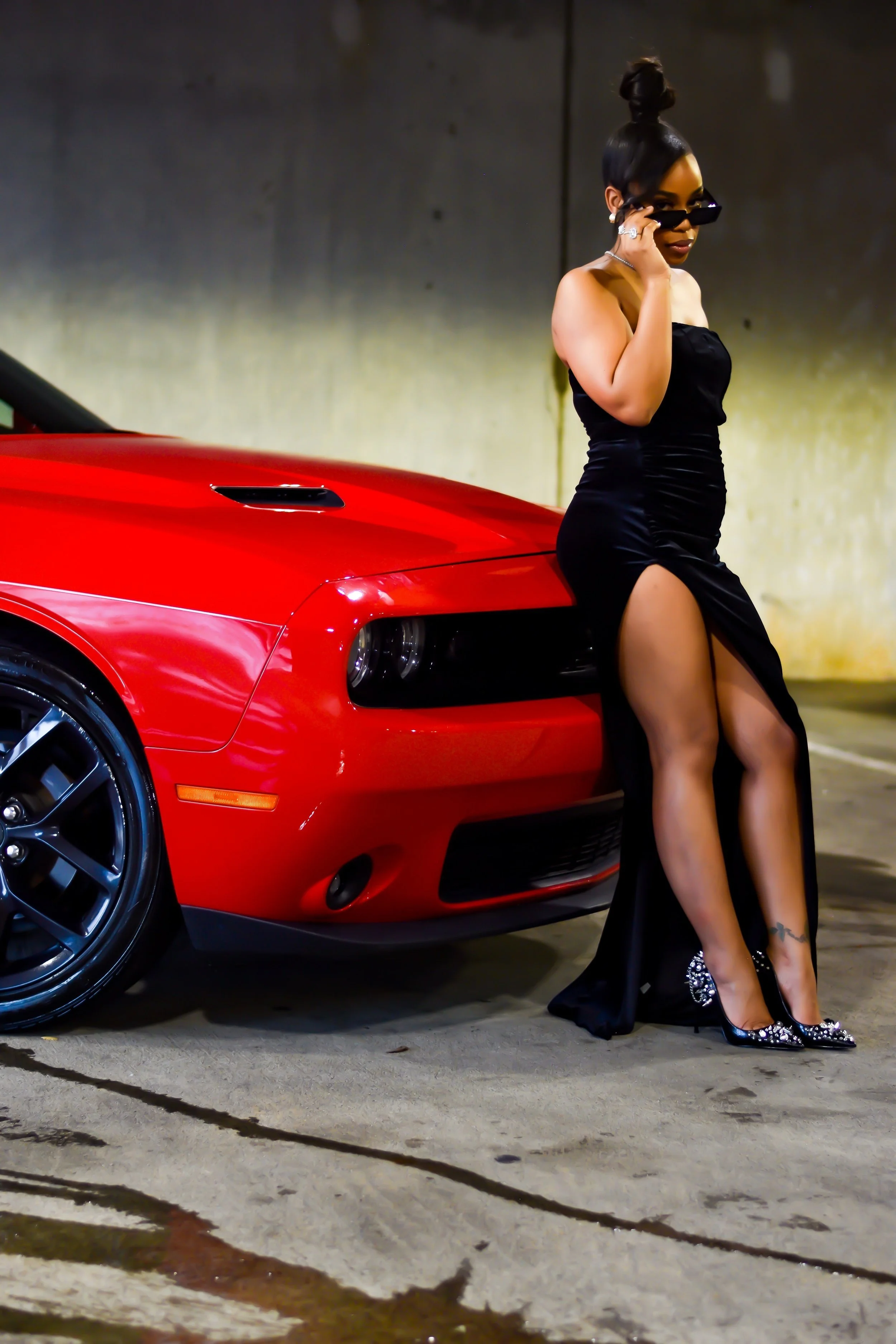 In this high-voltage editorial photoshoot, Dynasty Creatives brings to life a bold visual narrative of status, sensuality, and street-edge sophistication. Set against the sleek silhouette of a red luxury sports car, the story unfolds in a cinematic c