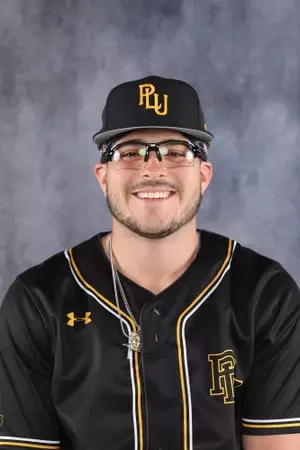Young man wearing a black baseball cap, glasses, and a black sports jersey with yellow accents, smiling in front of a gray background.