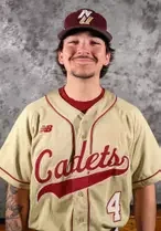 Young man wearing a vintage baseball jersey and cap, smiling against a gray background.