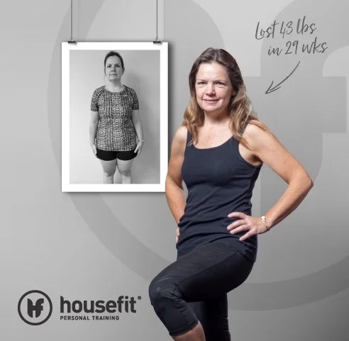 A woman standing in front of a gray background, smiling and showing her right side with her hand on her hip, wearing a black workout tank top and black pants. To her left is a framed photo of her former self, who appears heavier. Handwritten text indicates she lost 43 pounds in 29 weeks, and the bottom left features the housefit logo and the words "Personal Training."