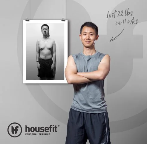 A man standing with arms crossed, smiling, in front of a gray background. A black-and-white photo of the same man shirtless and standing relaxed is hanging on the wall behind him. Handwritten text on the wall says, "Lost 22 lbs in 11 weeks." Logo for Housefit Personal Training is at the bottom left corner.