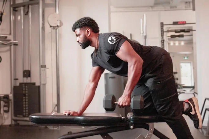 Housefit Trainer Wensley exercising with dumbbell on workout bench in gym