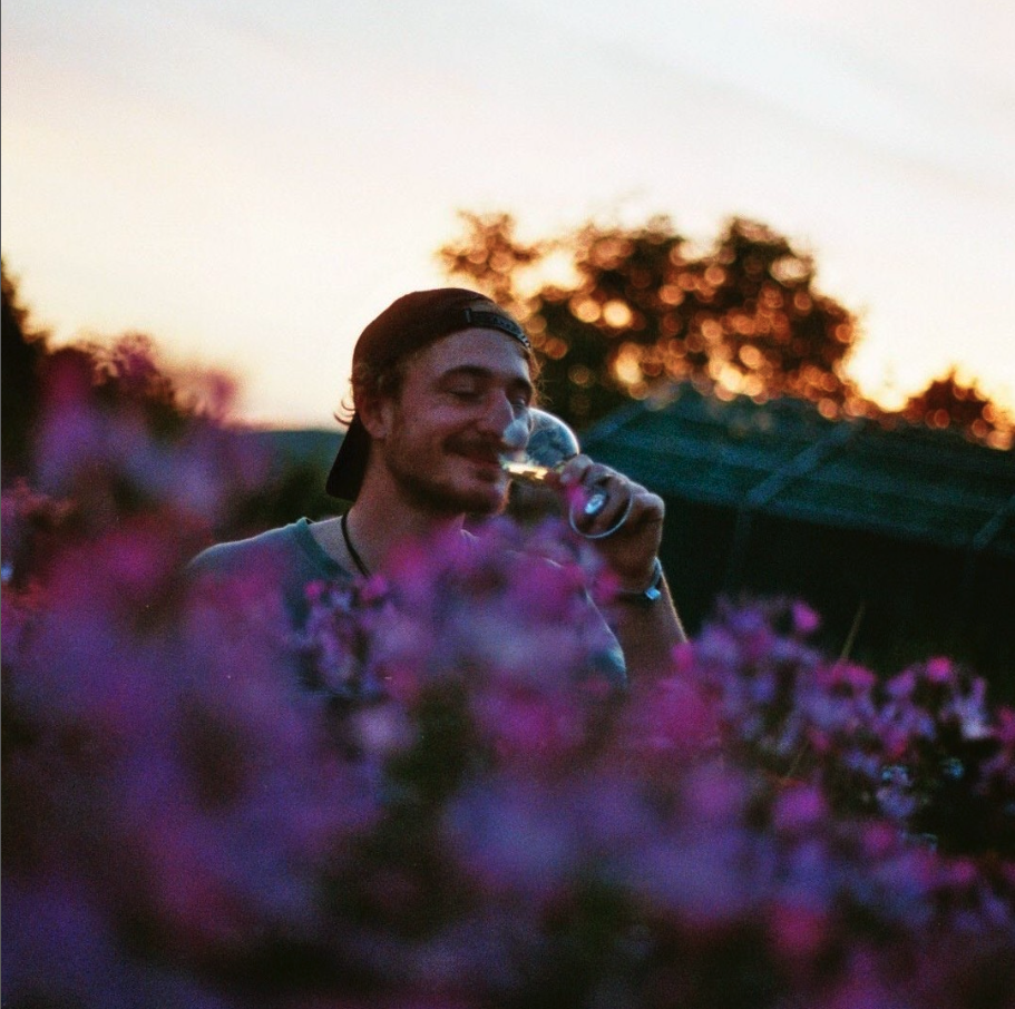 Winzer David Amling steht im Weinberg und richt voller Genuss in ein Glas Natural Wine.