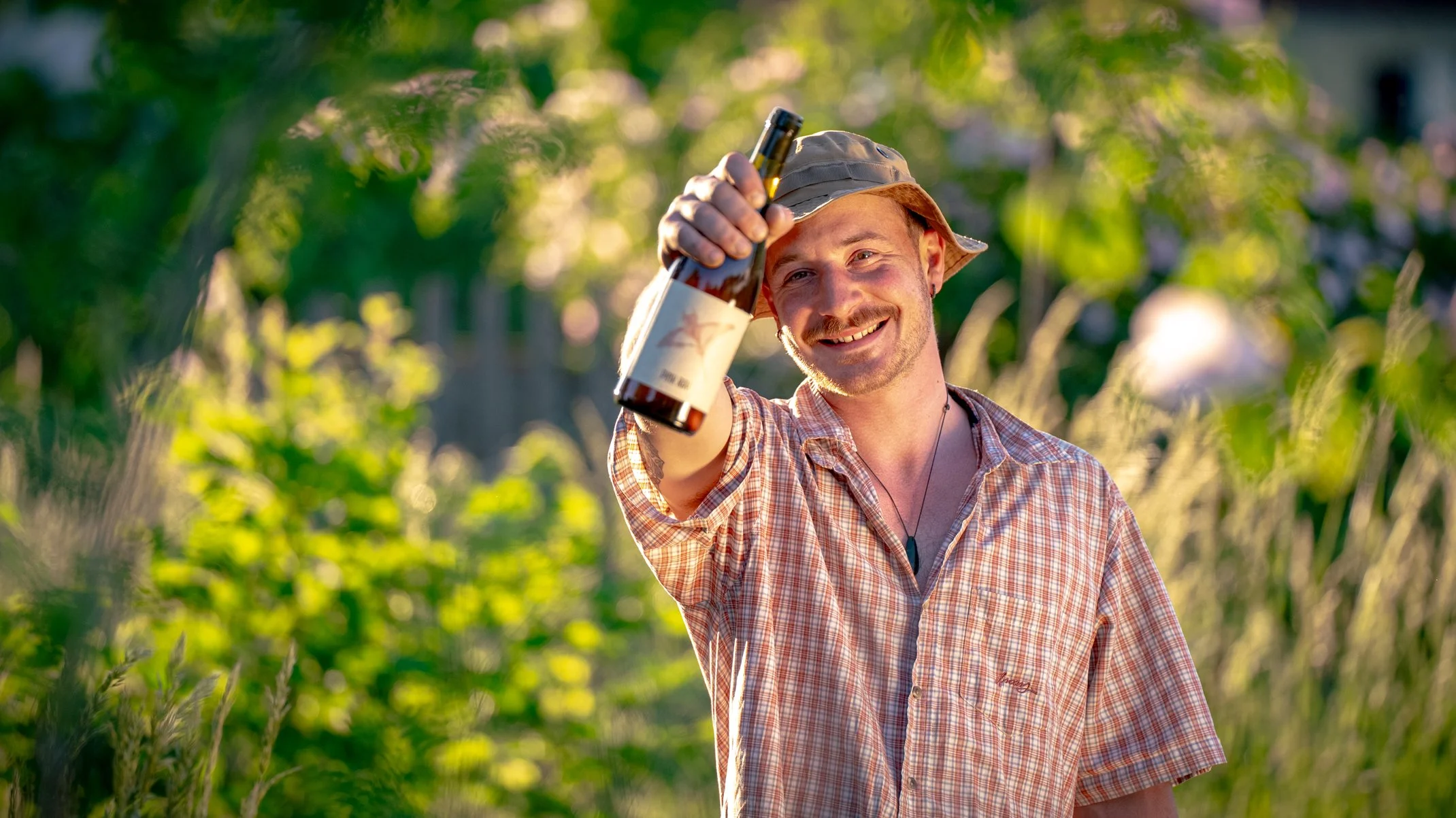 Winzer David Amling in Sonnenhut und kariertem Hemd präsentiert Pink Ray, ein Pinot Gris und Bacchus Naturwein aus Franken.