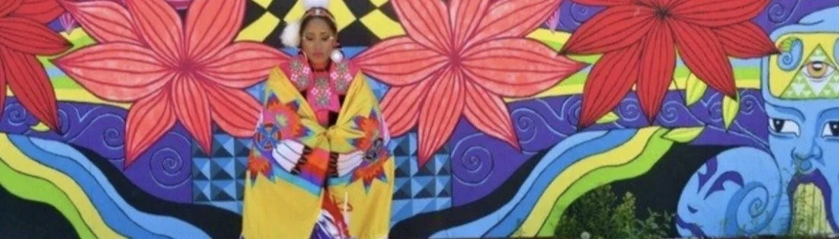A woman dressed in traditional Japanese kimono standing in front of a colorful mural with large red flowers and abstract designs.