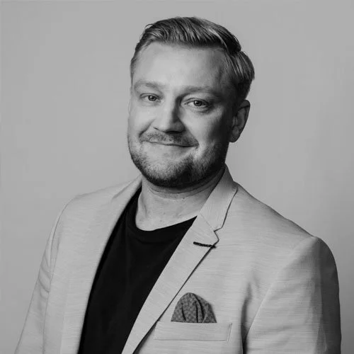 Henkilön poseeraus mustavalkoisessa valokuvassa, hymyilevä ja hyvin pukeutunut