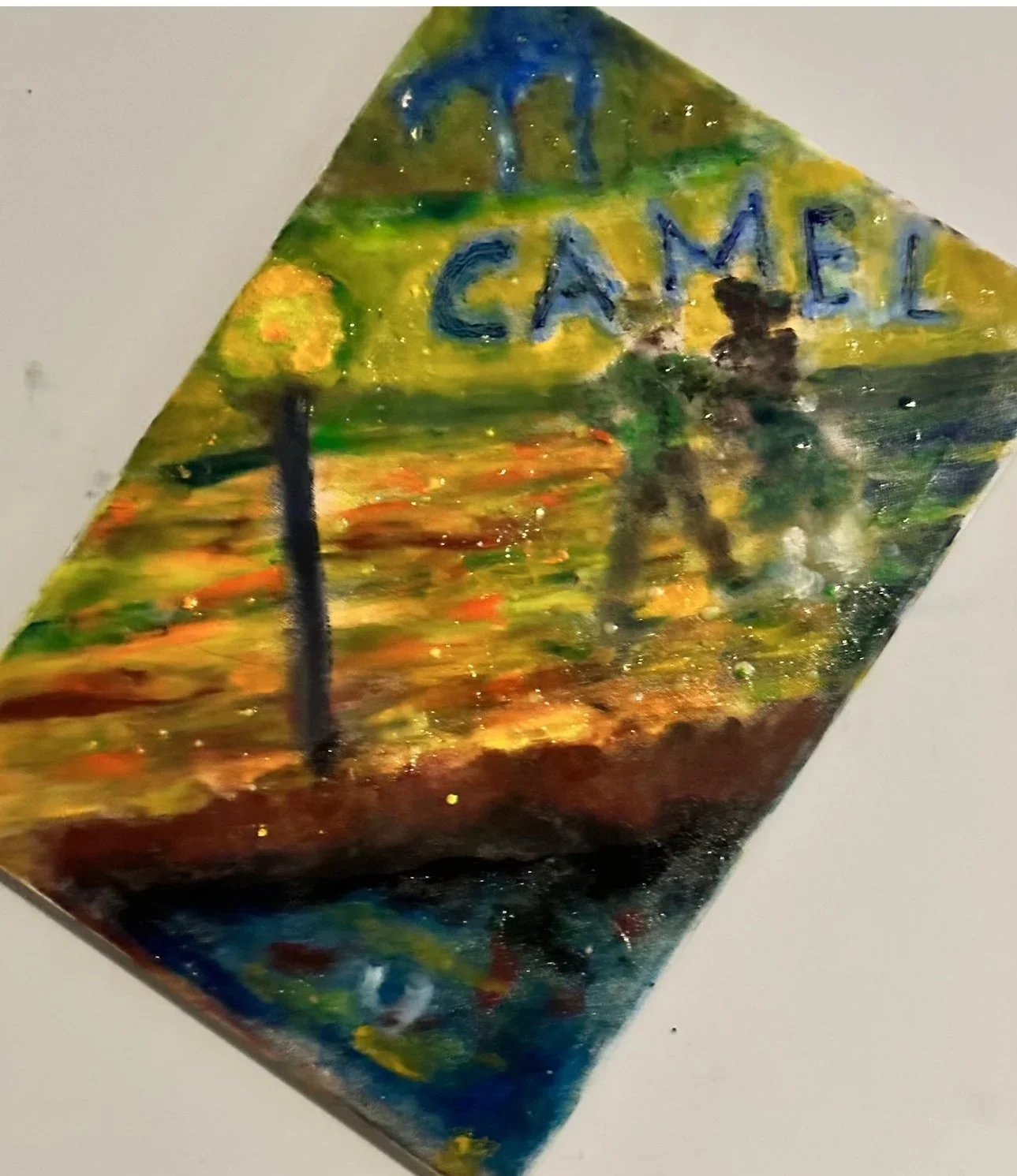 Colorful hand-painted sign with the words "CAME" and a background of sunset with trees and water.