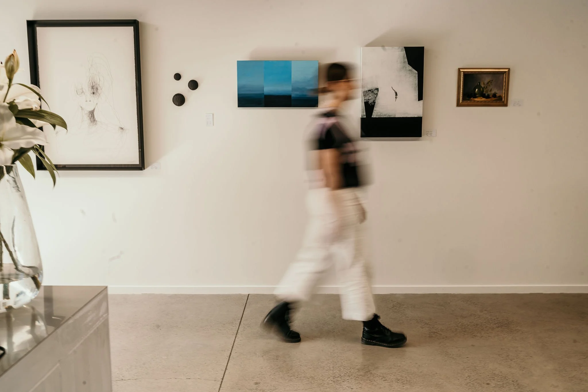 Woman walking through an art space with framed and unframed artworks in the background