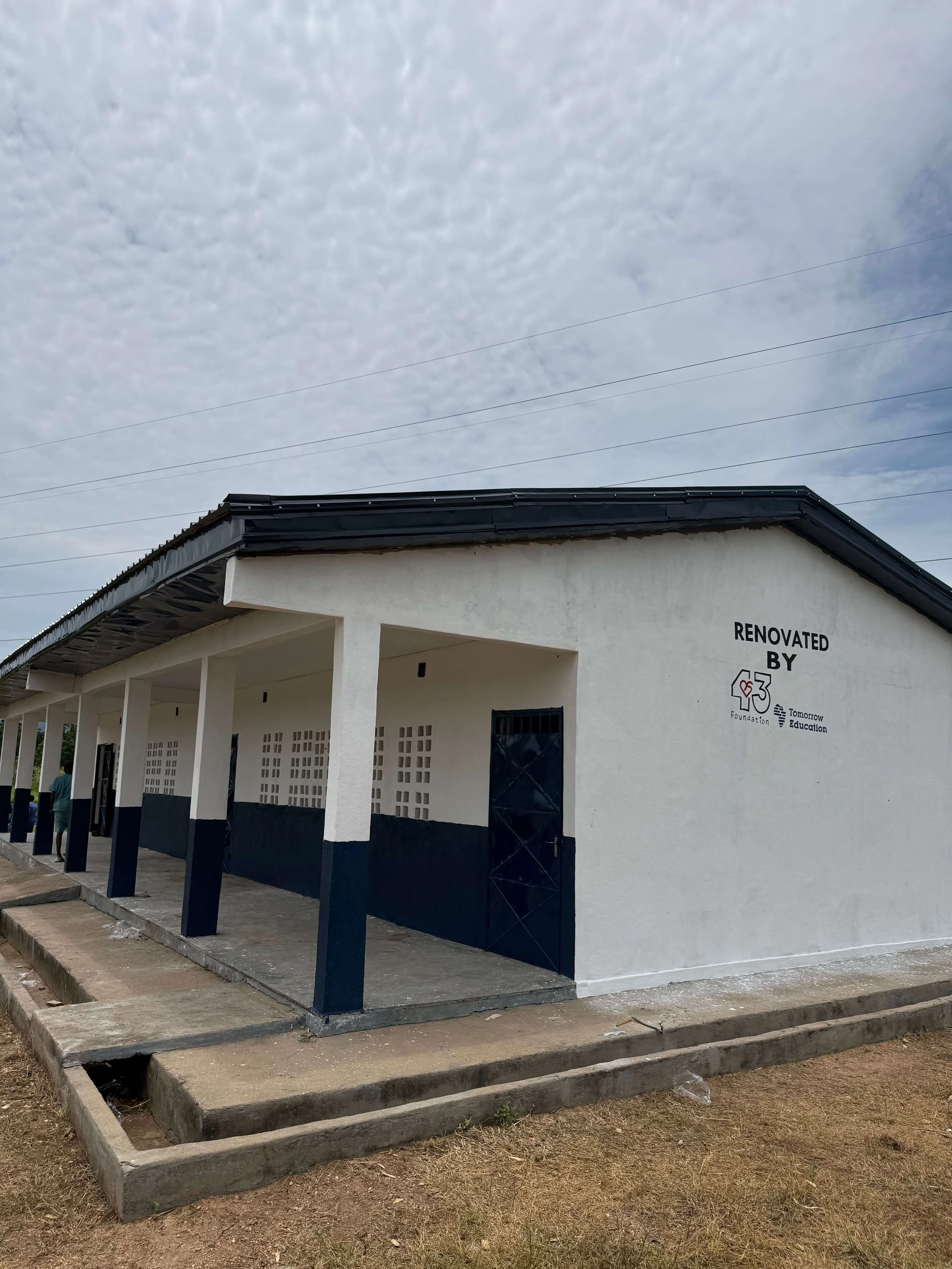 Renovated white-and-black community building with covered walkway, labeled with the Tomorrow Education Foundation logo.