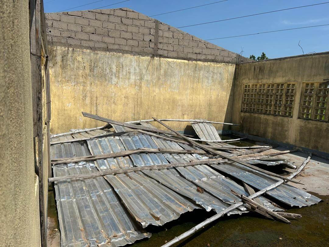 Collapsed corrugated metal roof and wooden supports inside a weathered concrete building