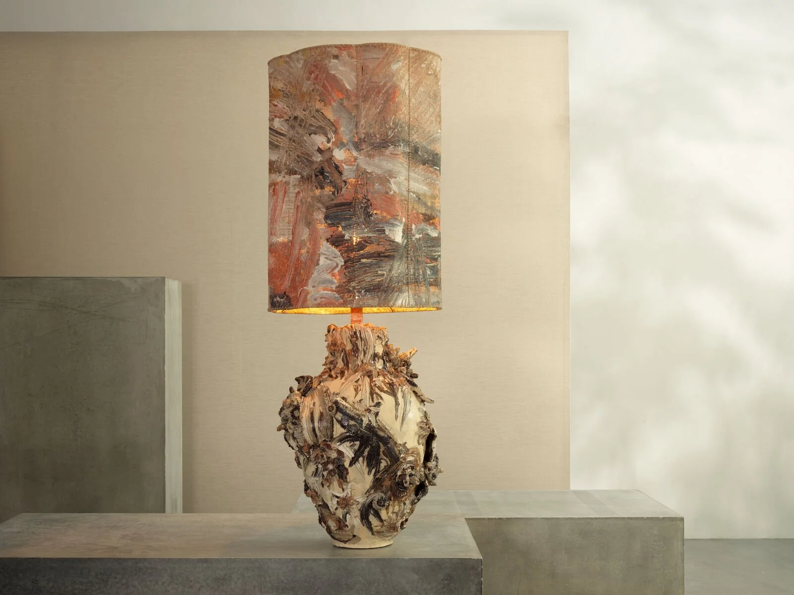 Artistic table lamp with a textured base resembling driftwood and a matching abstract lampshade, placed on a concrete surface in a modern interior.