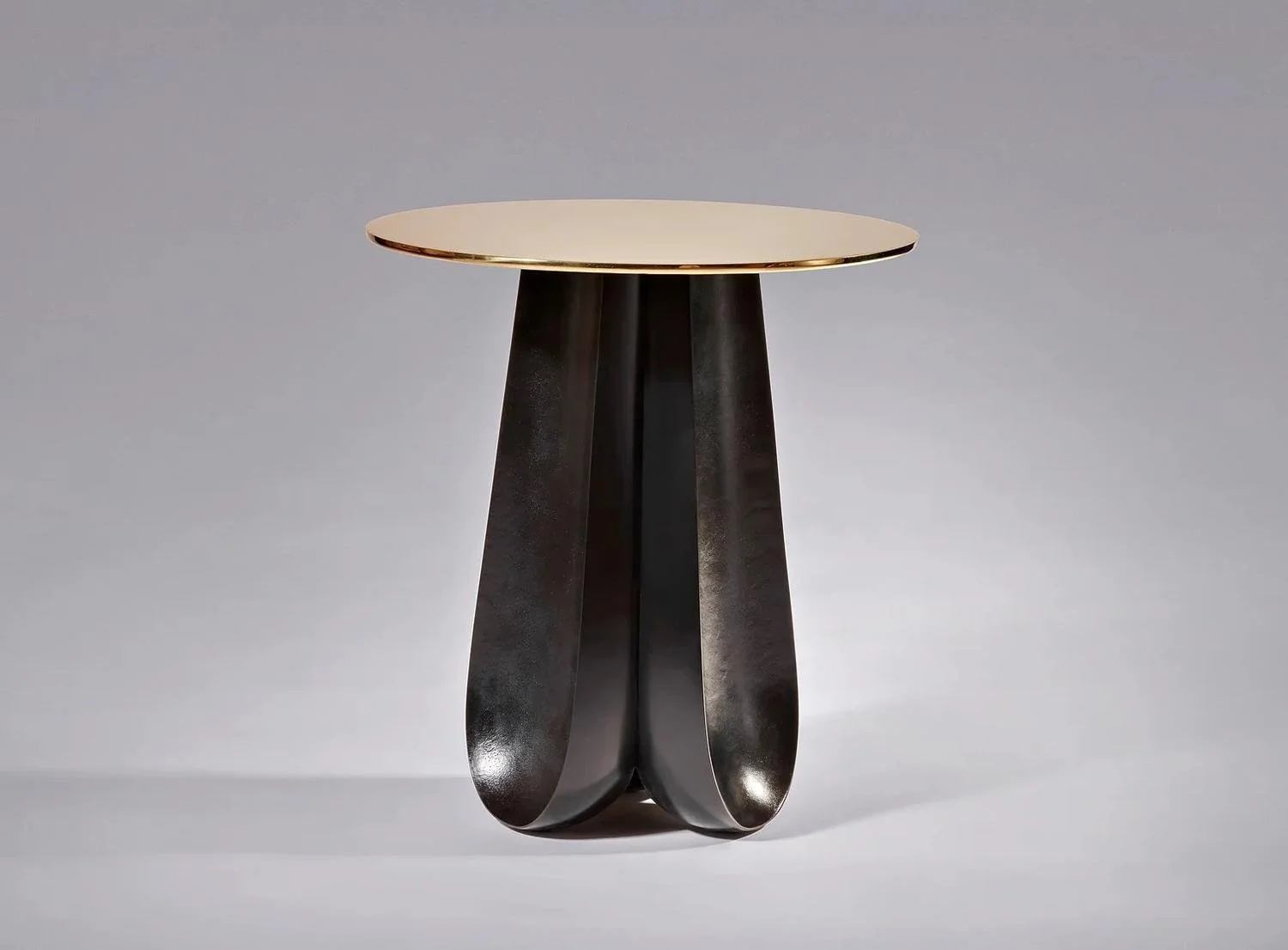 Modern side table with a round beige top and black curved legs in a minimalist style