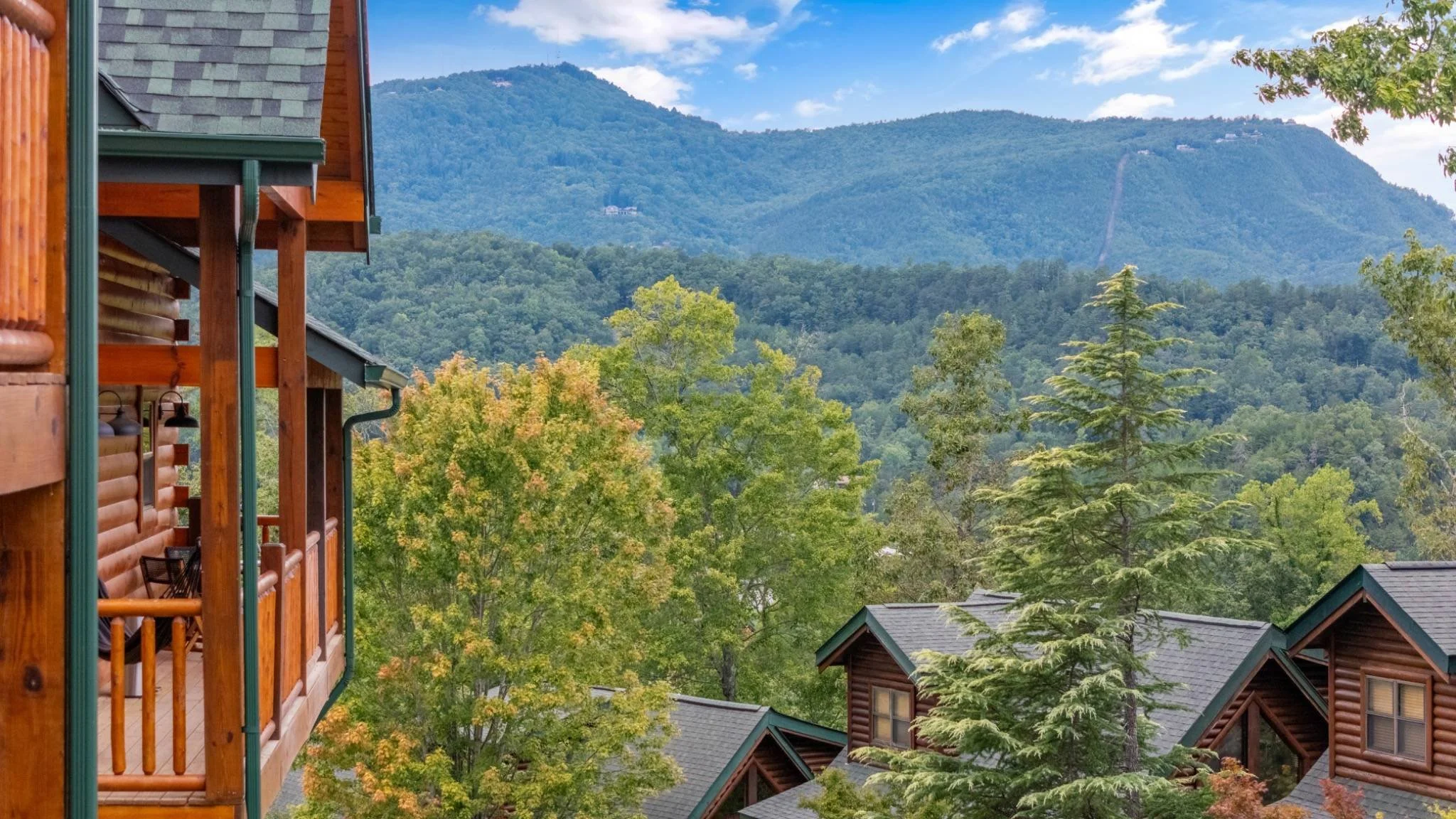 Smoky Mountain view from cabin balcony at Bearfoot Bliss, surrounded by trees and log cabins in Pigeon Forge