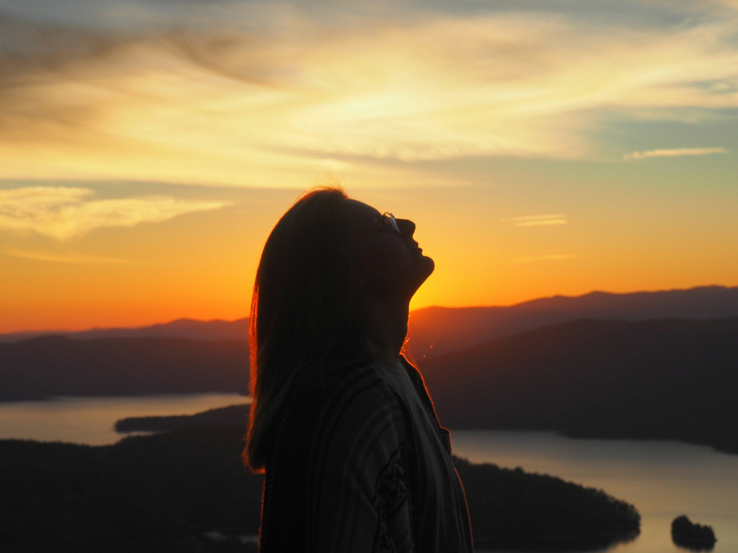 “Woman looking up at a sunset sky, reflecting on values, direction, and personal growth.”