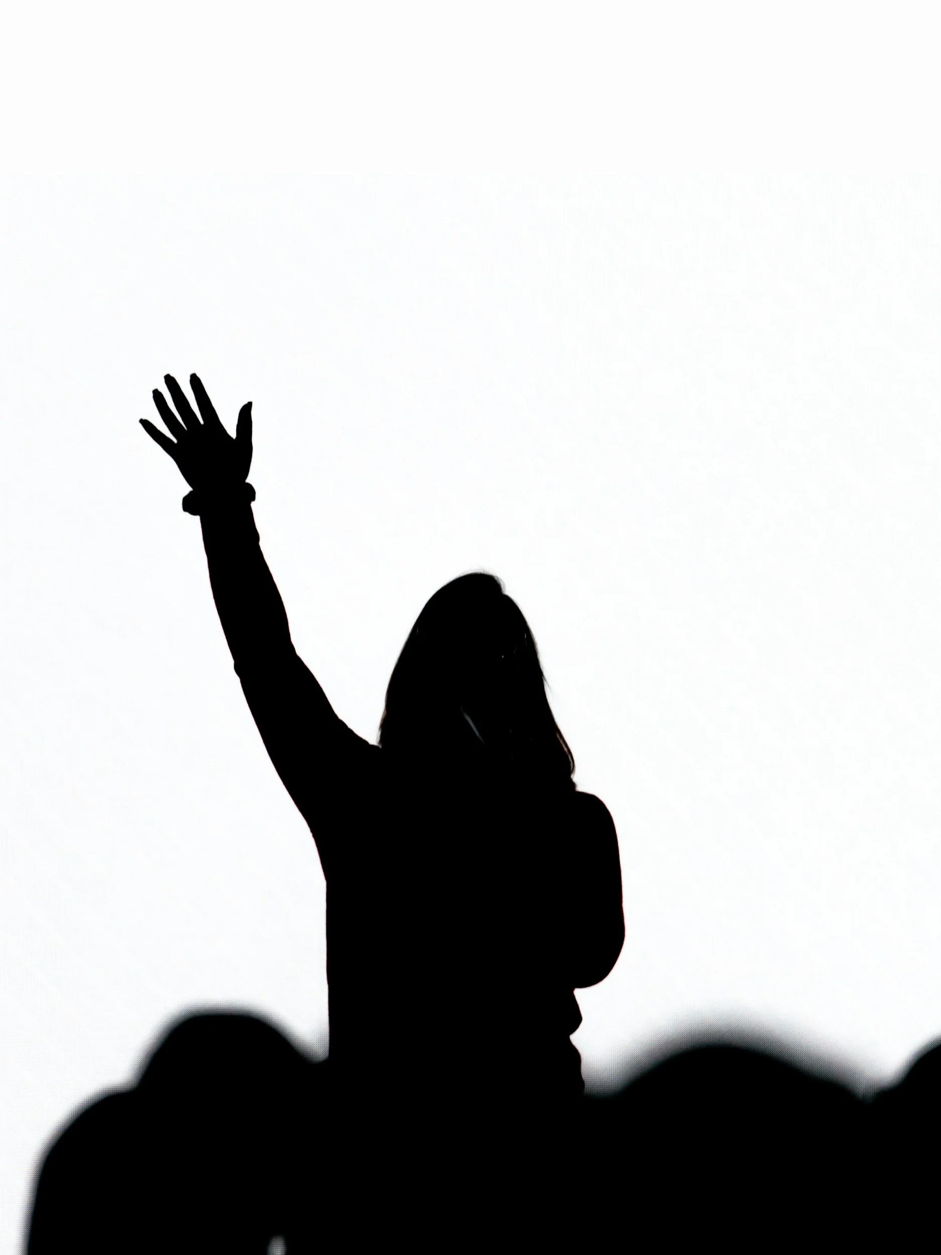 Silhouette of a woman with her hand raised, against a white background.