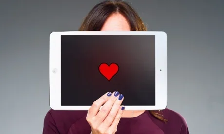 "Woman holding a tablet with a red heart icon, symbolising online connection, emotional support, and digital community."
