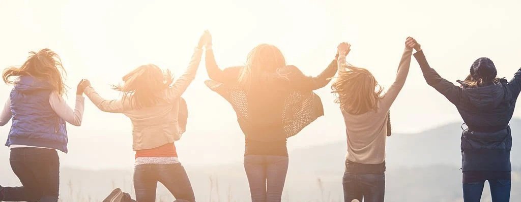 Three women holding hands and jumping together — symbolising support, joy, and community for women on GLP-1 medication.