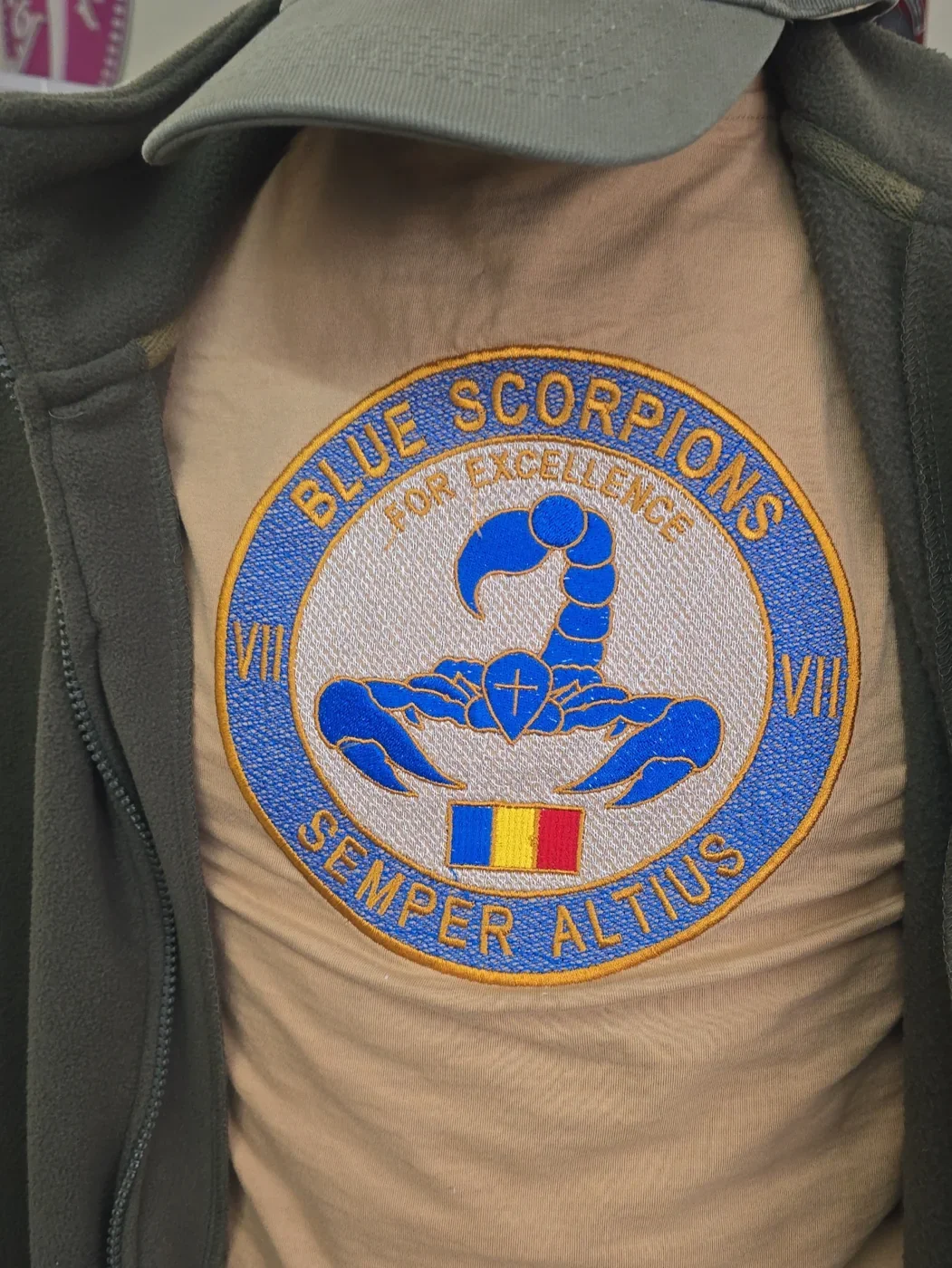 Koszulka z haftem Blue Scorpions prezentowana pod rozpiętym oliwkowym polarem na manekinie
