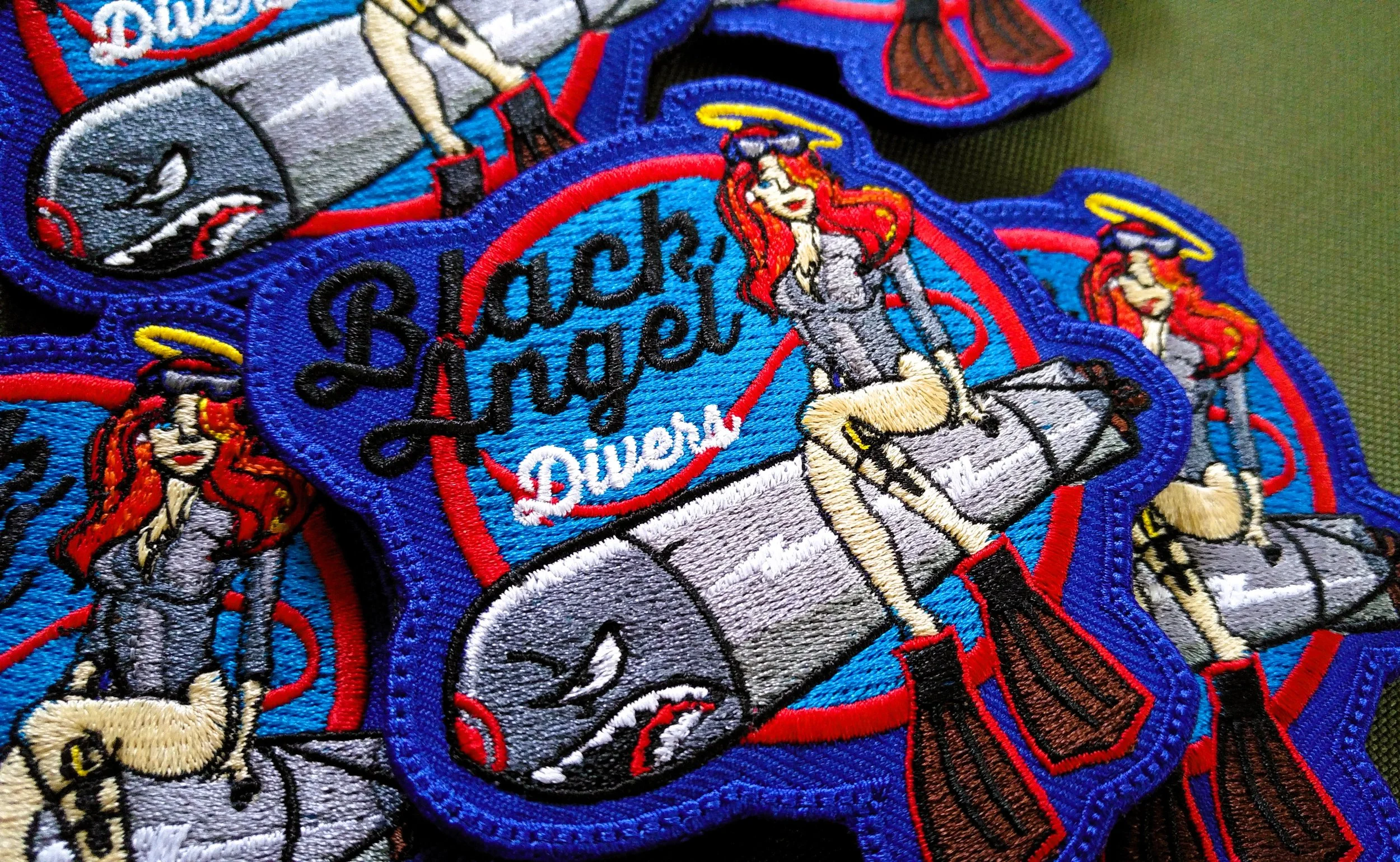 Kolorowe naszywki Black Angel Divers z rudowłosą postacią siedzącą na butli nurkowej