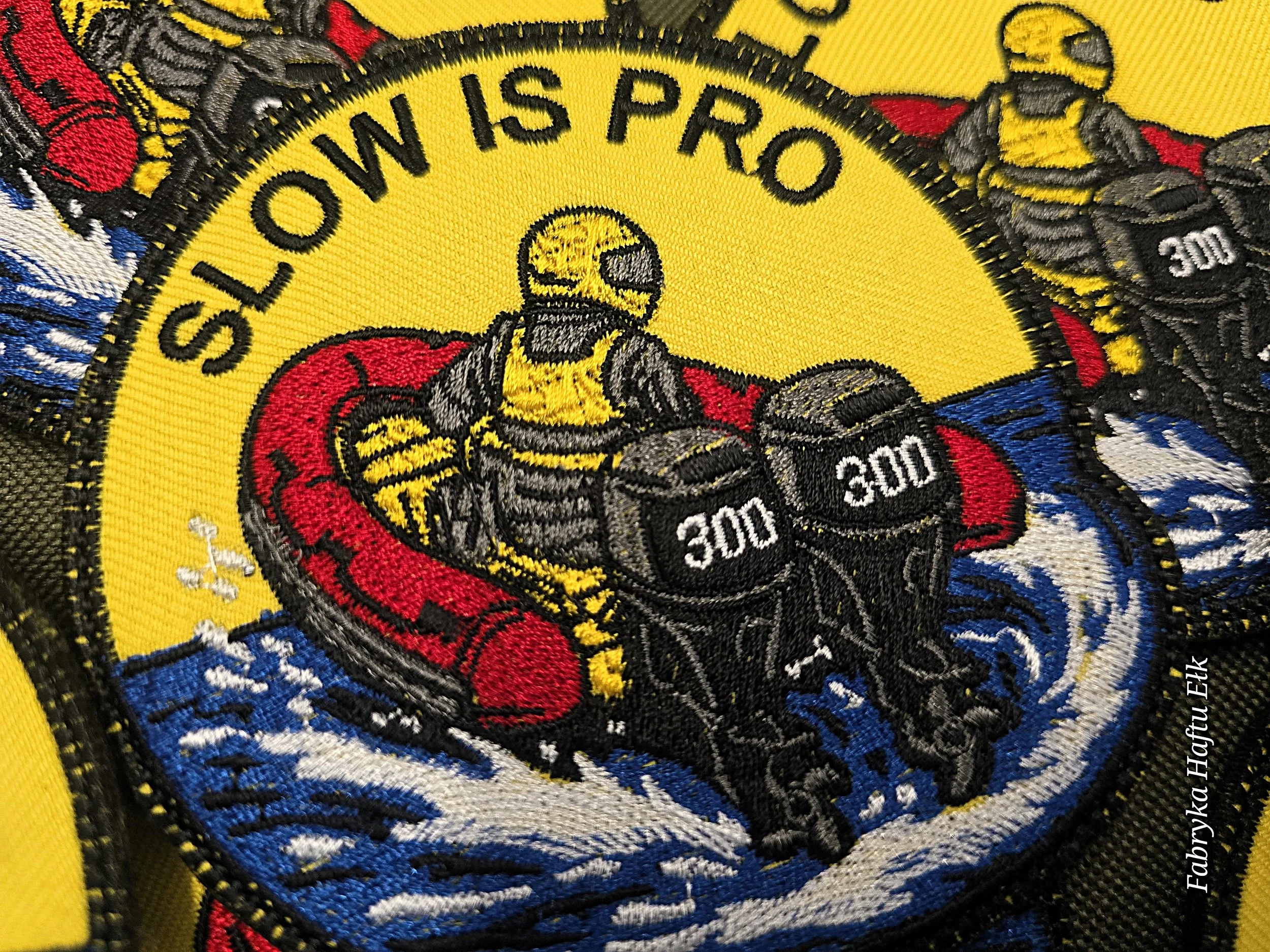 Kolorowa naszywka haftowana Slow Is Pro z postacią prowadzącą czerwony ponton motorowy