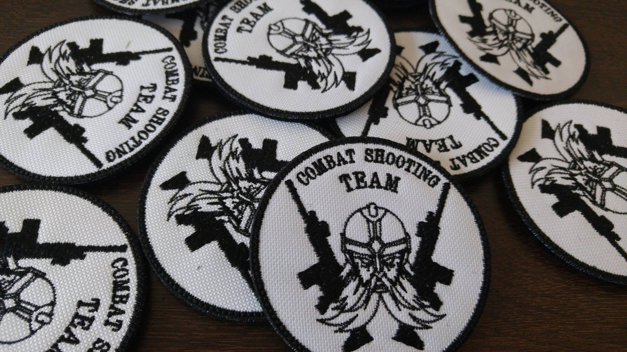 Biało-czarne naszywki Combat Shooting Team z głową wojownika i skrzyżowanymi karabinami