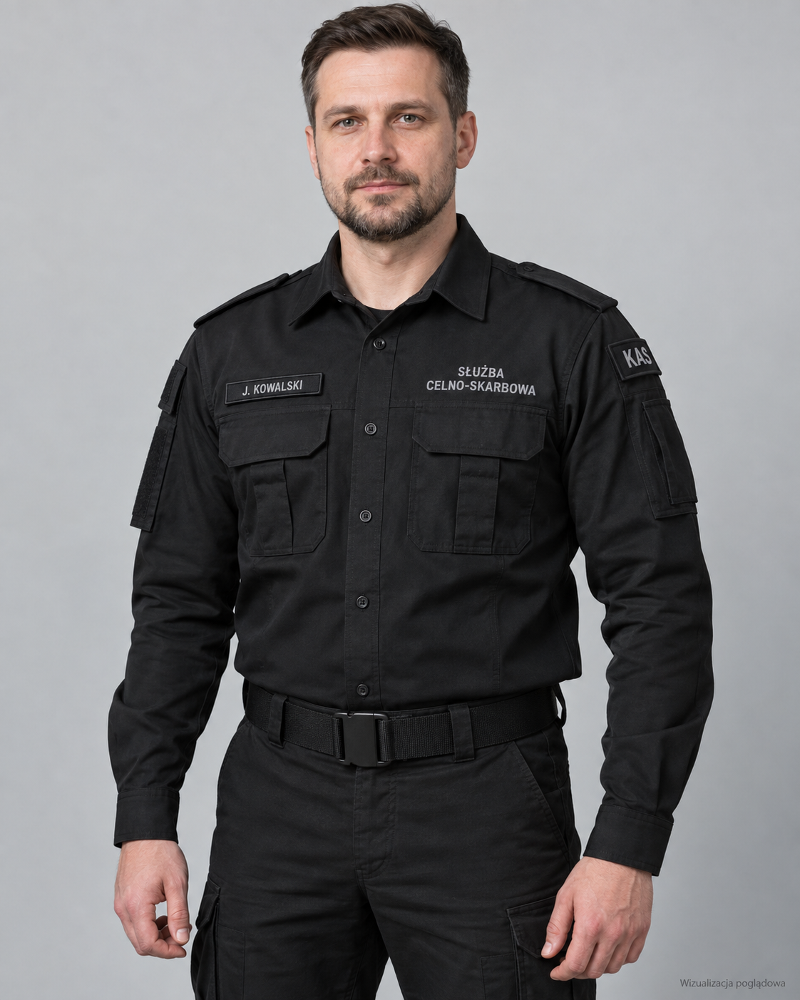 A man in a black uniform with Polish text and patches, standing against a plain gray background.