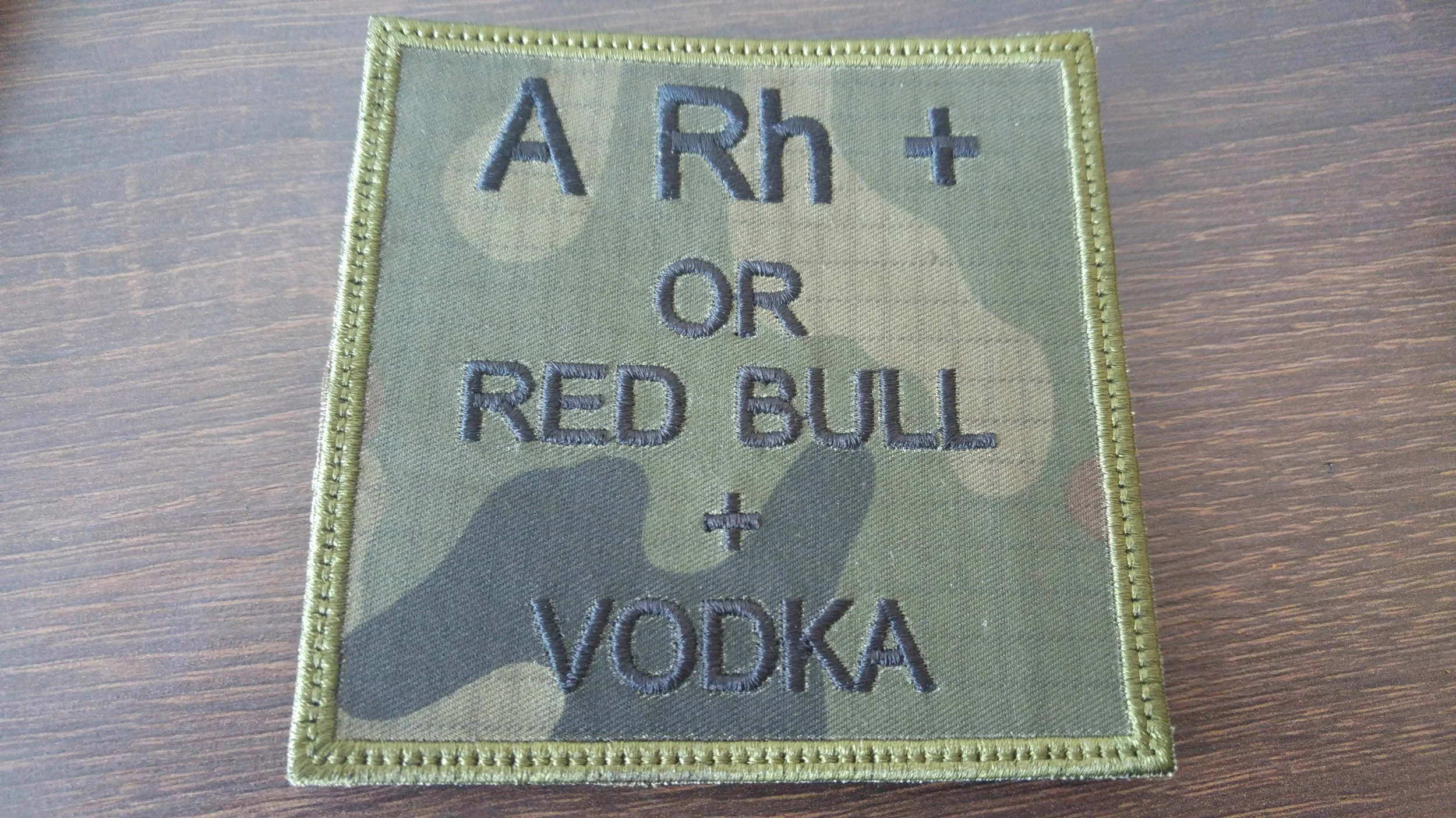 Patch with embroidered text that reads 'A R h t OR RED BULL + YOKA' on a camouflage background.