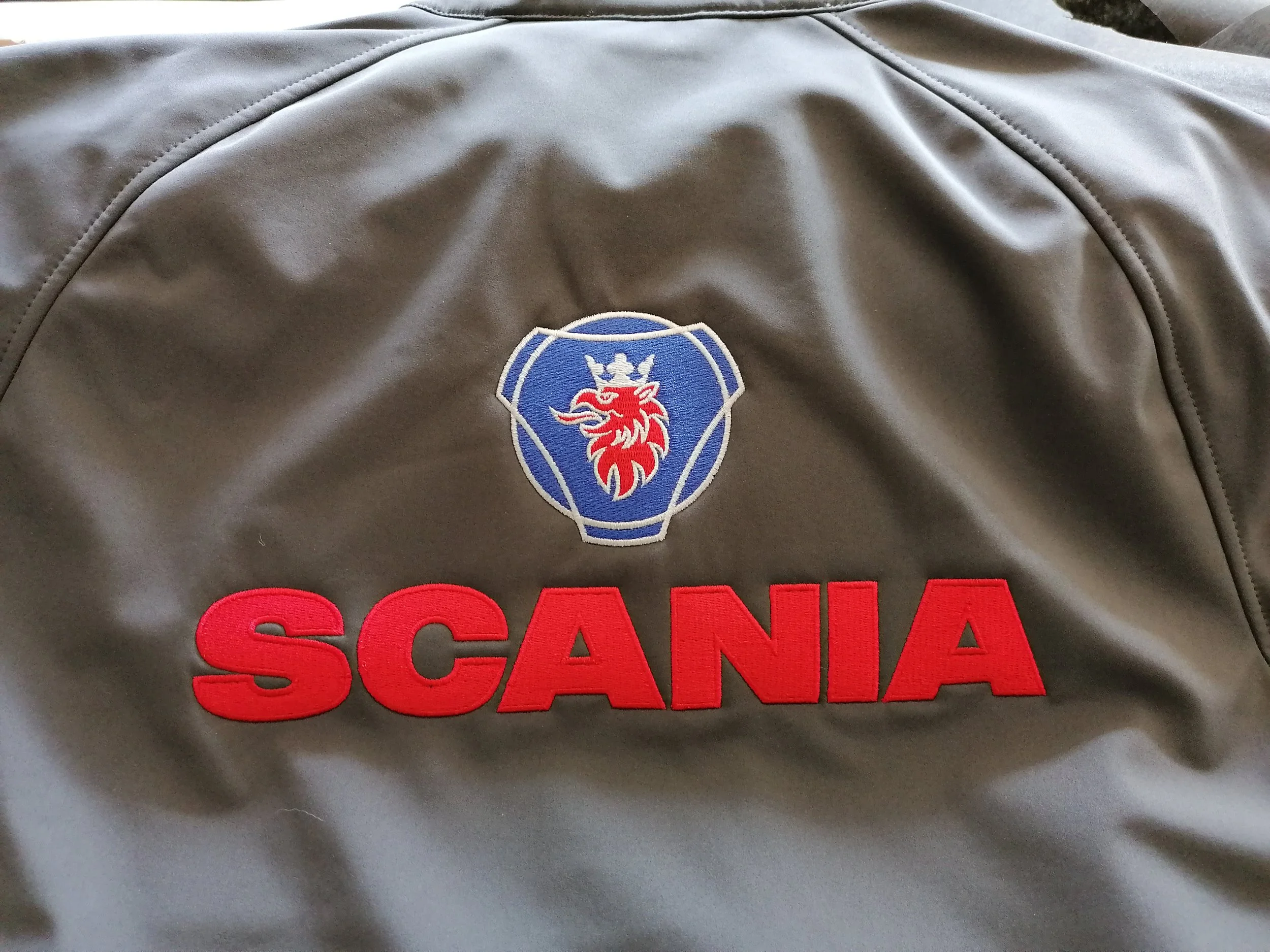 A gray jacket featuring a Scotty logo dark gray and a red word 'SCANA' embroidered on it.