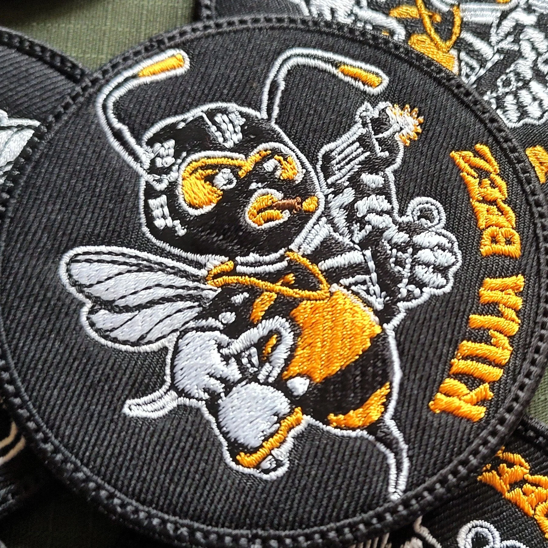 Czarna naszywka Ninja Beez z żółto-białą pszczołą w stroju wojownika i żółtym napisem