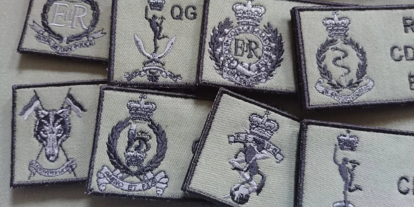 Zbliżenie symboli formacji na brytyjskich naszywkach indywidualnych z detalami koron i drobnymi haftowanymi napisami