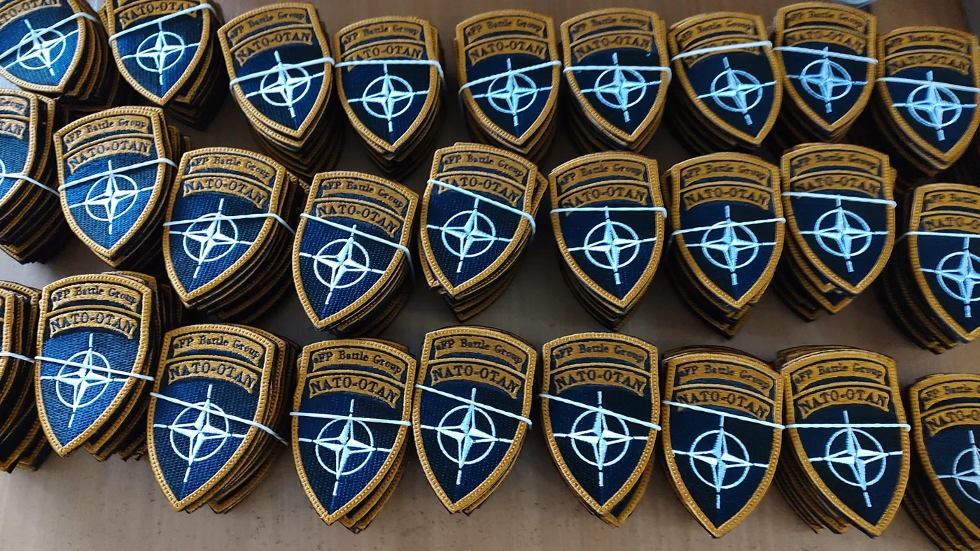 Rzędy gotowych haftowanych tarcz eFP Battle Group NATO-OTAN z zamówienia amerykańskich żołnierzy