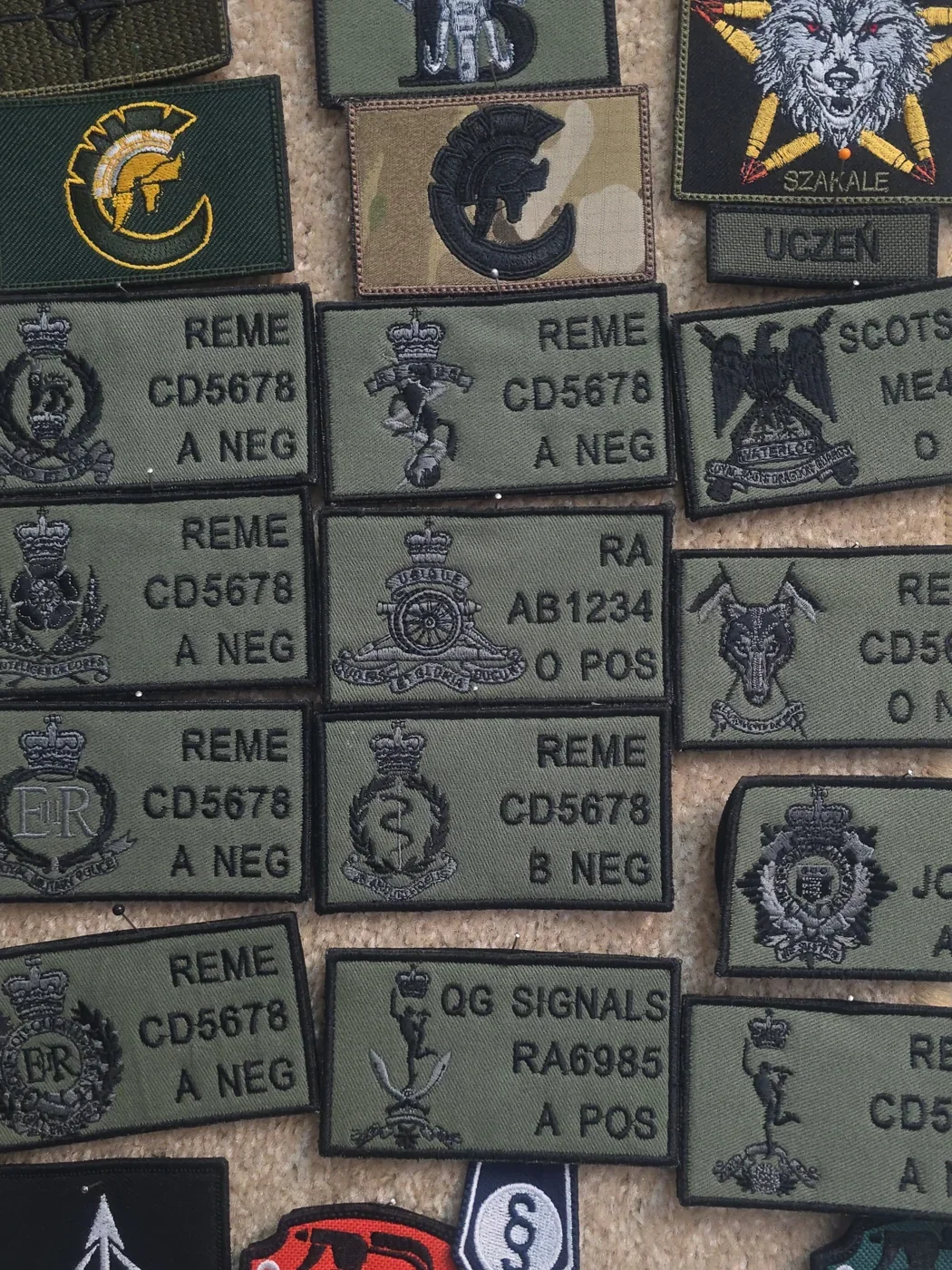 Zestaw zielonych indywidualnych naszywek brytyjskich z symbolami regimentów i polami identyfikacyjnymi
