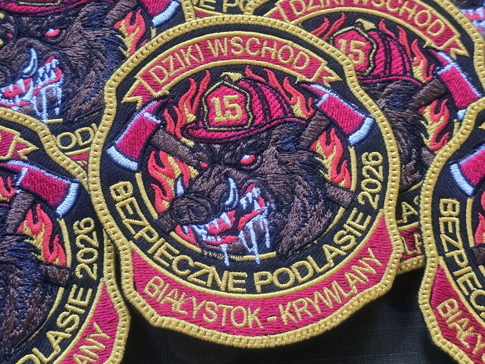 Kolorowe naszywki strażackie z dzikiem w hełmie i napisem Bezpieczne Podlasie
