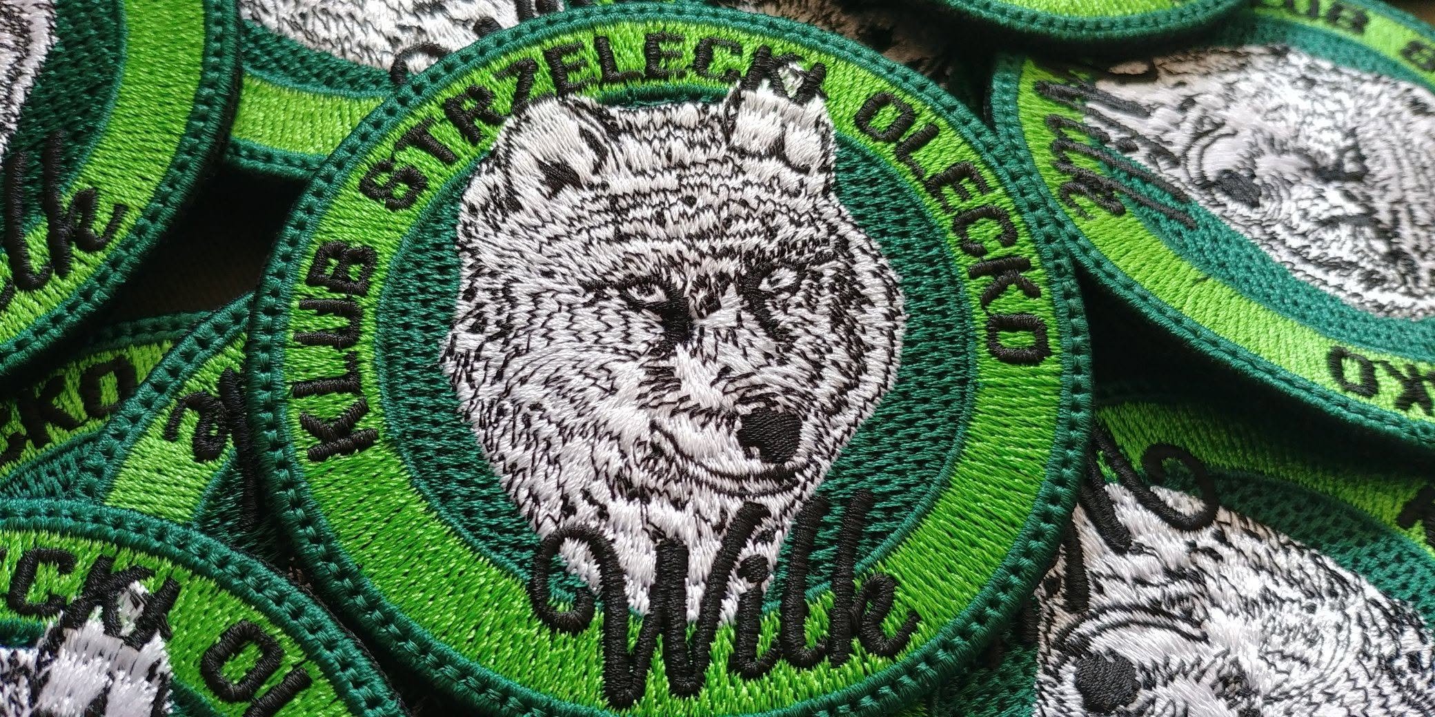 Haftowane naszywki Klubu Strzeleckiego Wilk z głową wilka na zielonym tle