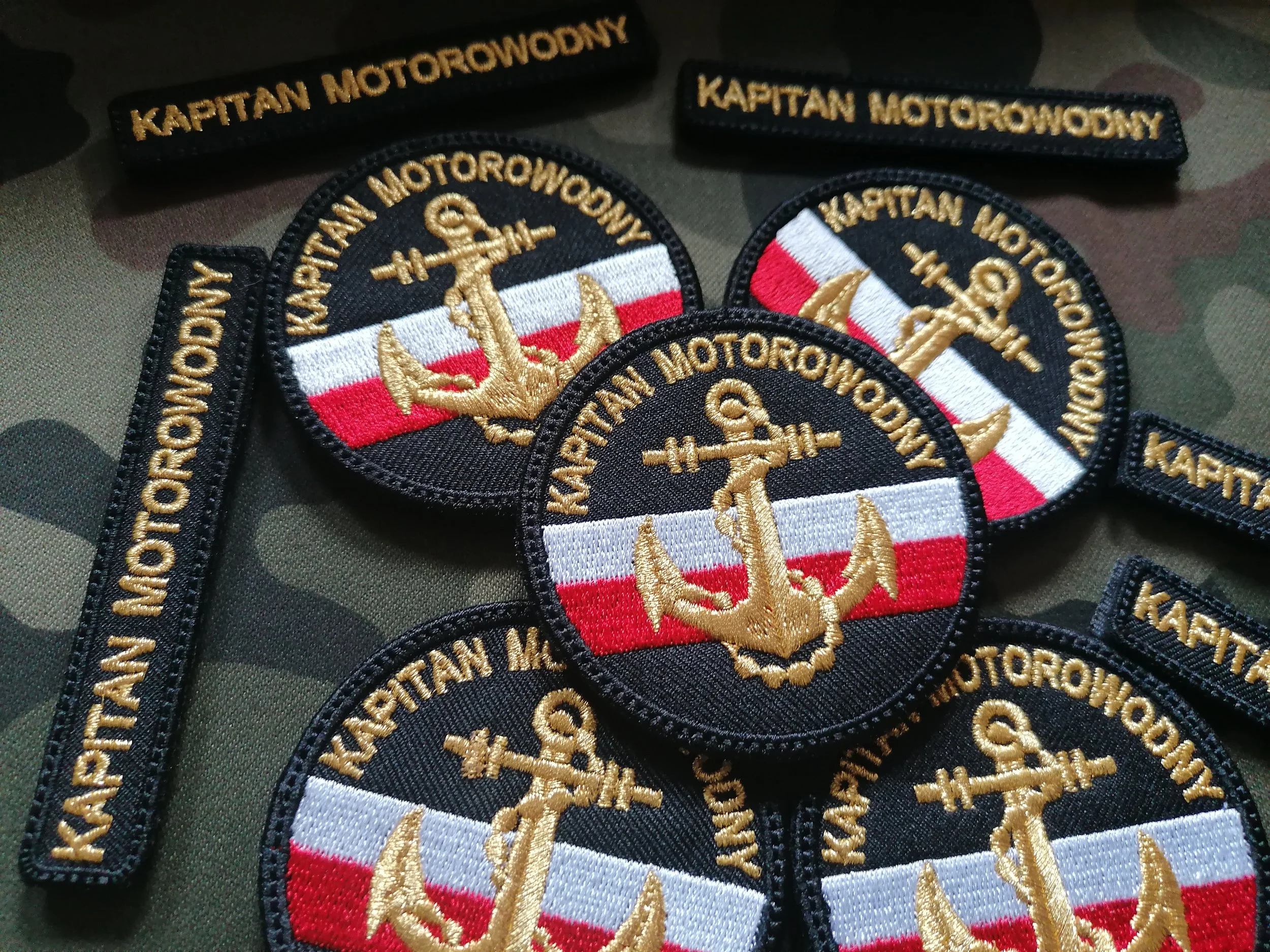 Czarne naszywki Kapitan Motorowodny ze złotą kotwicą na biało-czerwonym tle oraz prostokątne oznaczenia