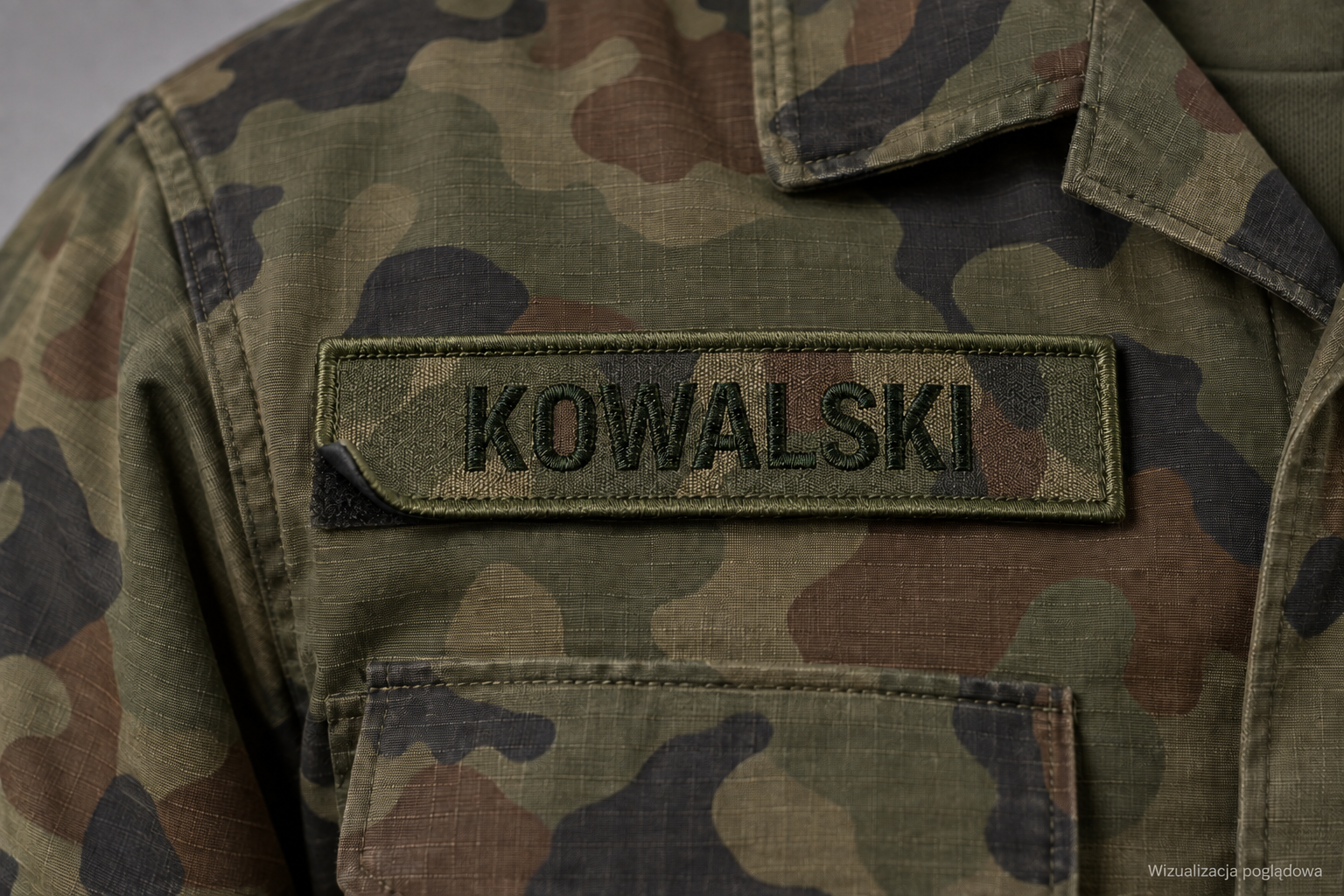 Oliwkowy imiennik KOWALSKI z ciemnym haftowanym napisem na mundurze w kamuflażu