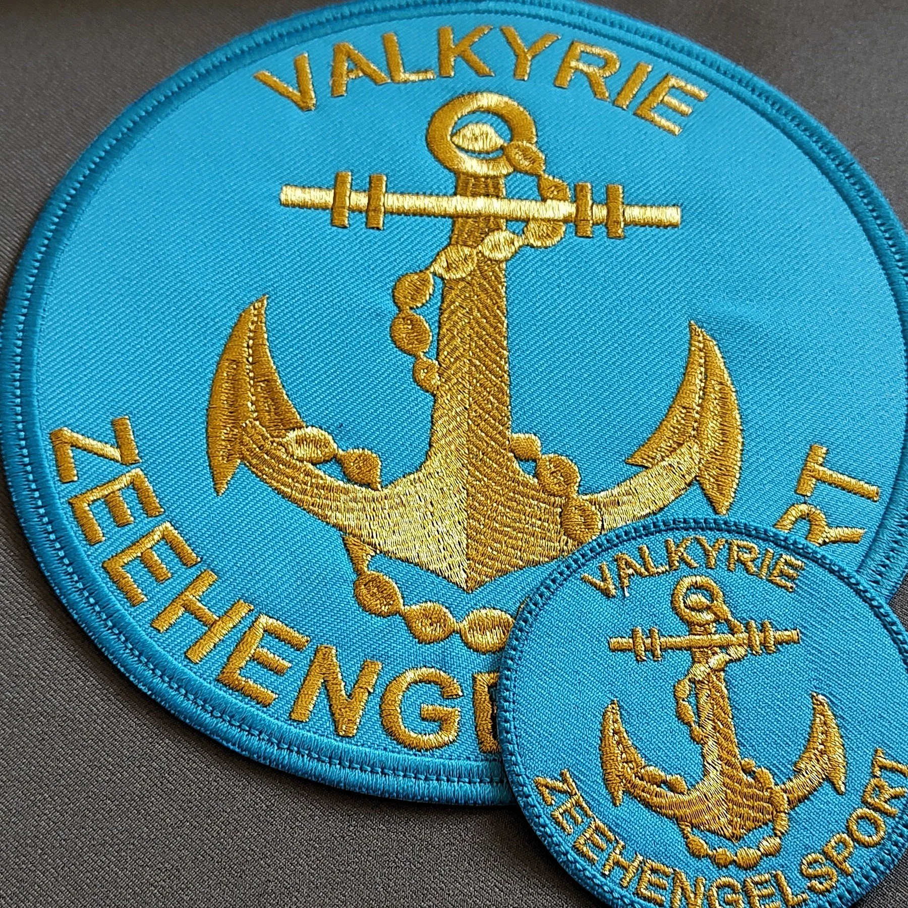 Turkusowe naszywki haftowane ze złotą kotwicą i łańcuchem, z mniejszym emblematem Valkyrie